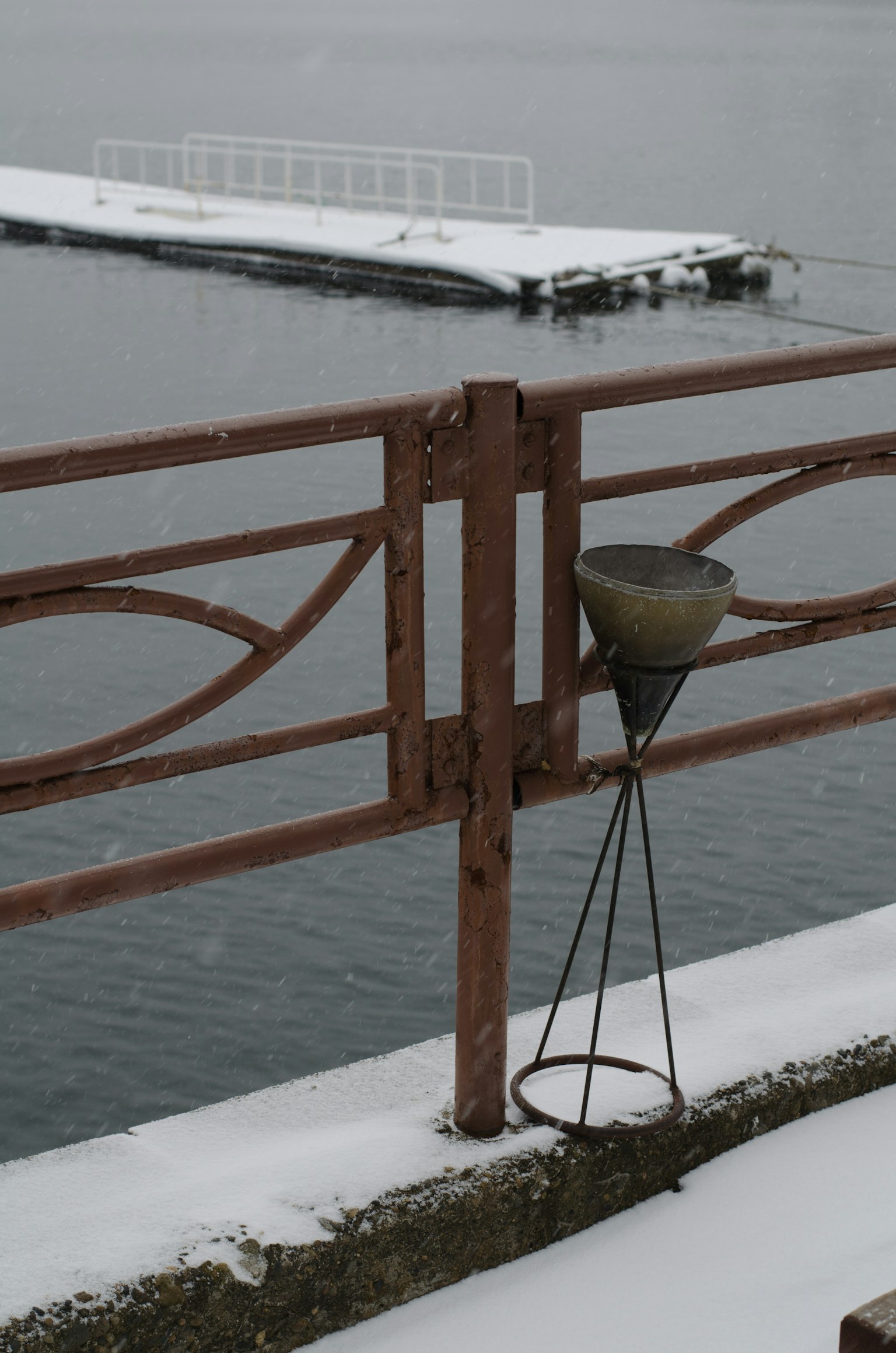 Bord de l'eau recouvert de neige avec une rambarde en métal et un dispositif suspendu