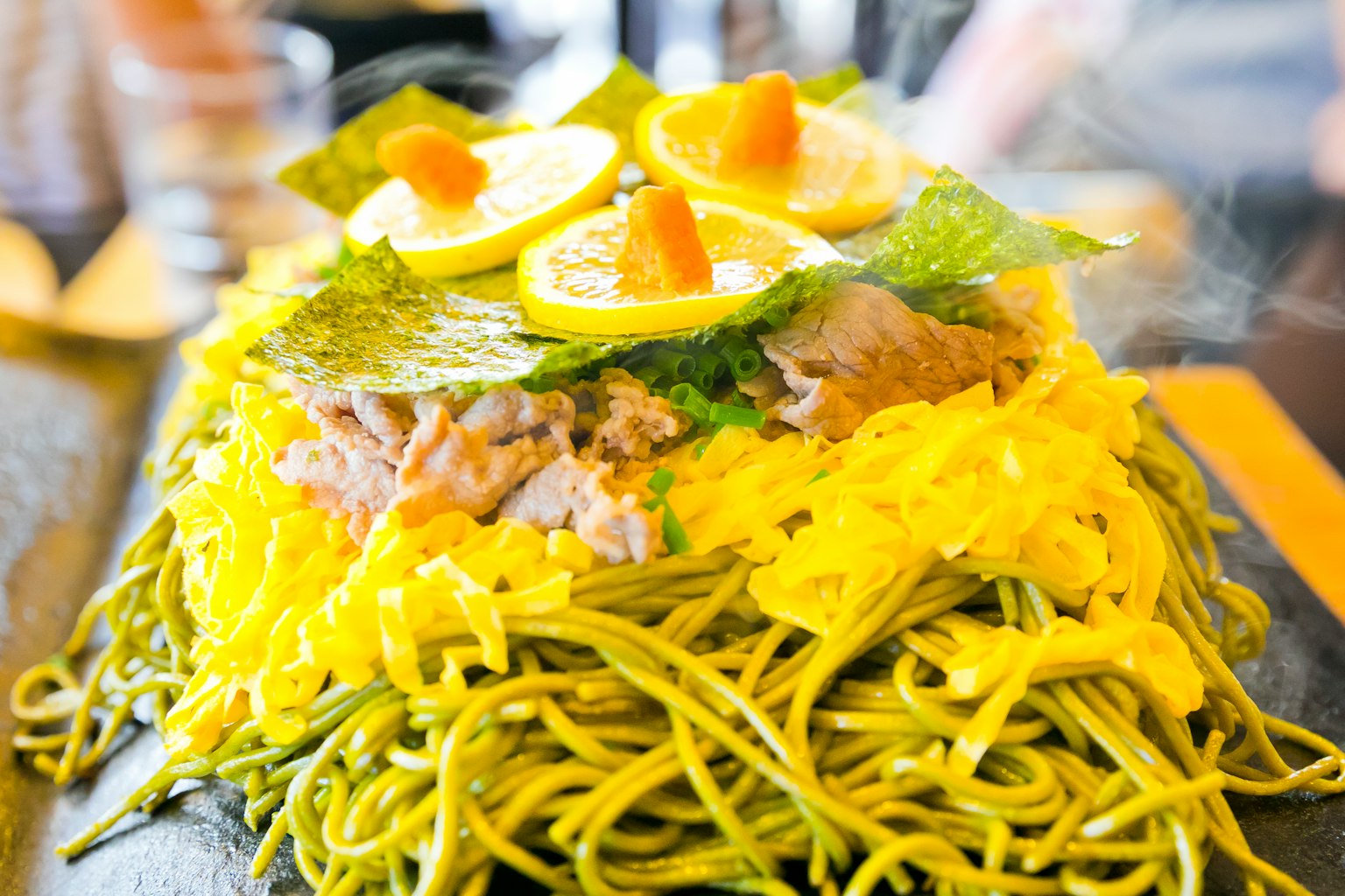Plat avec des nouilles vertes garnies de tranches de citron et de légumes