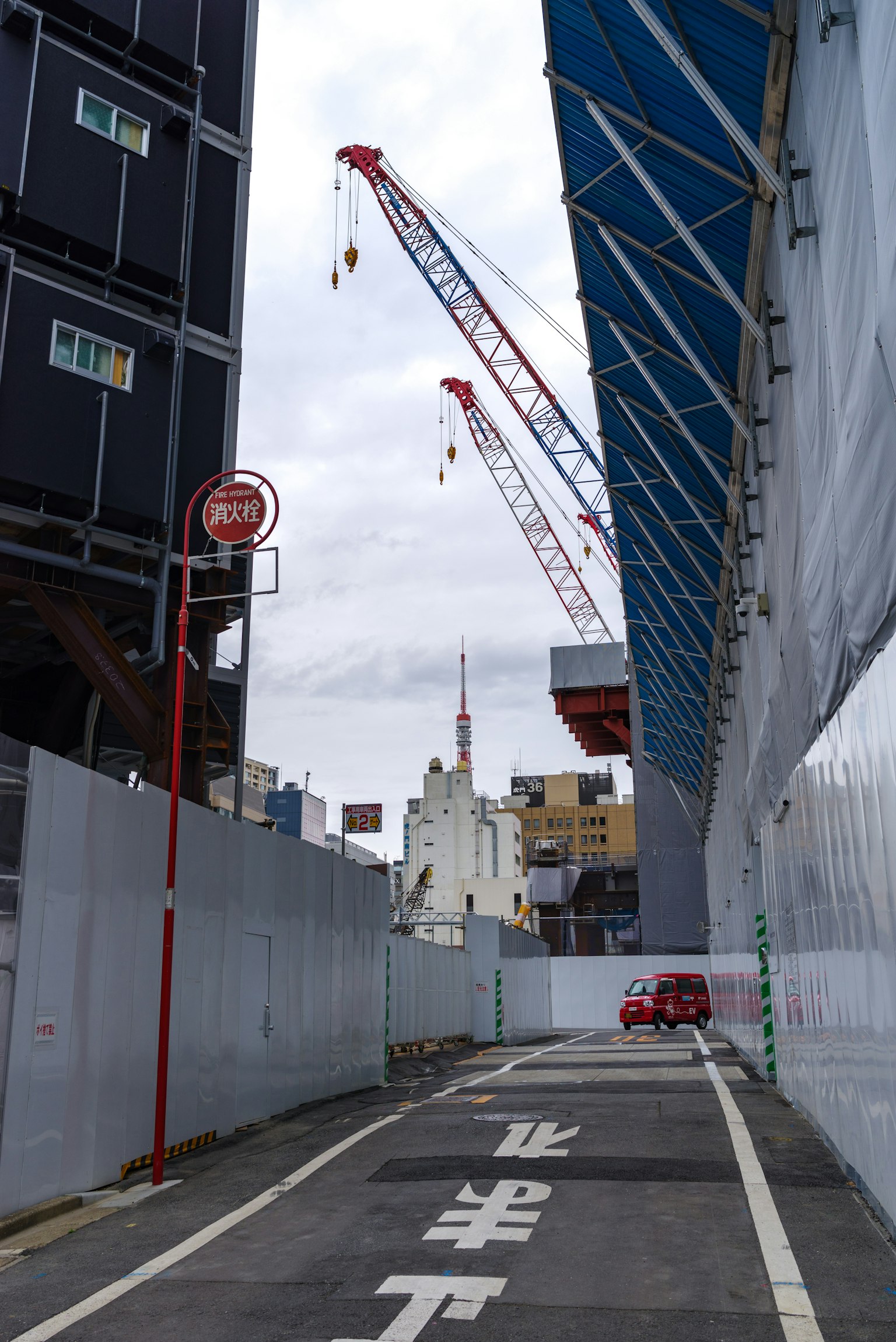 Vista de calle de un sitio de construcción con grúas y un techo azul