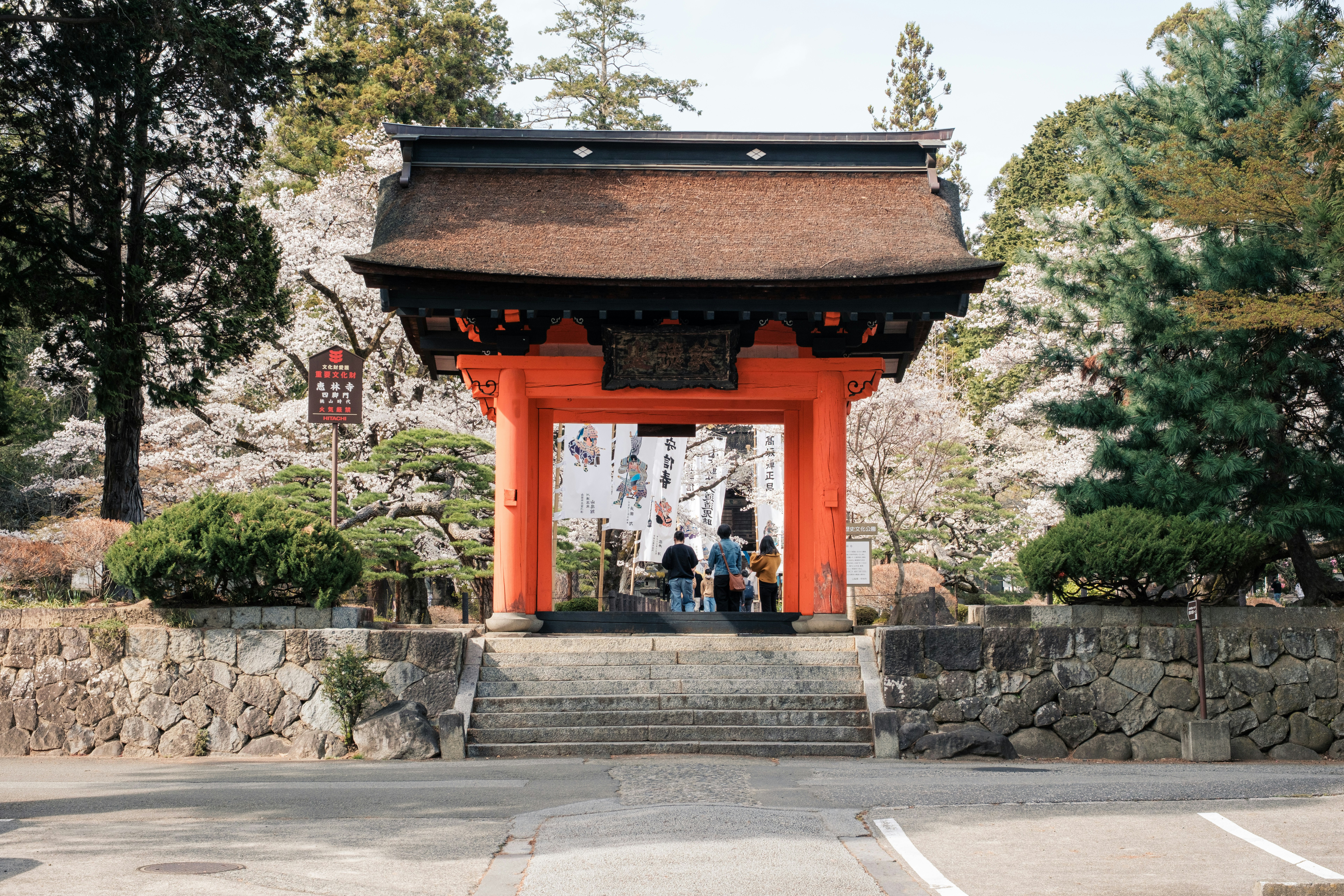 石段の前に立つ朱色の鳥居と参拝者のいる神社の入口