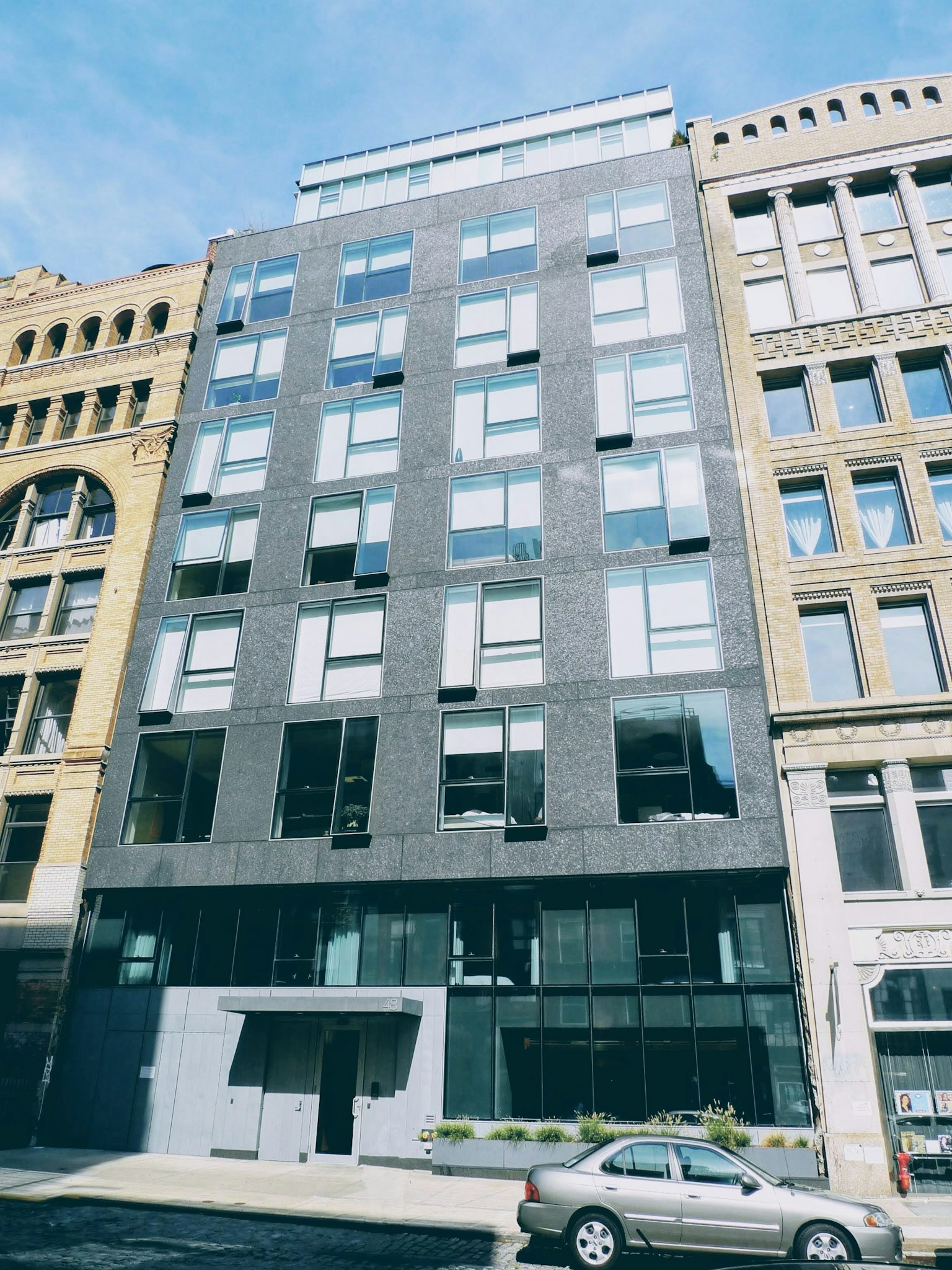 Edificio moderno con fachada negra ubicado en una calle con arquitectura histórica