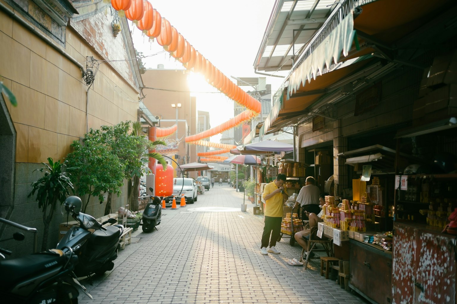 Jalan sempit dengan toko dan sepeda motor yang diterangi oleh matahari terbenam