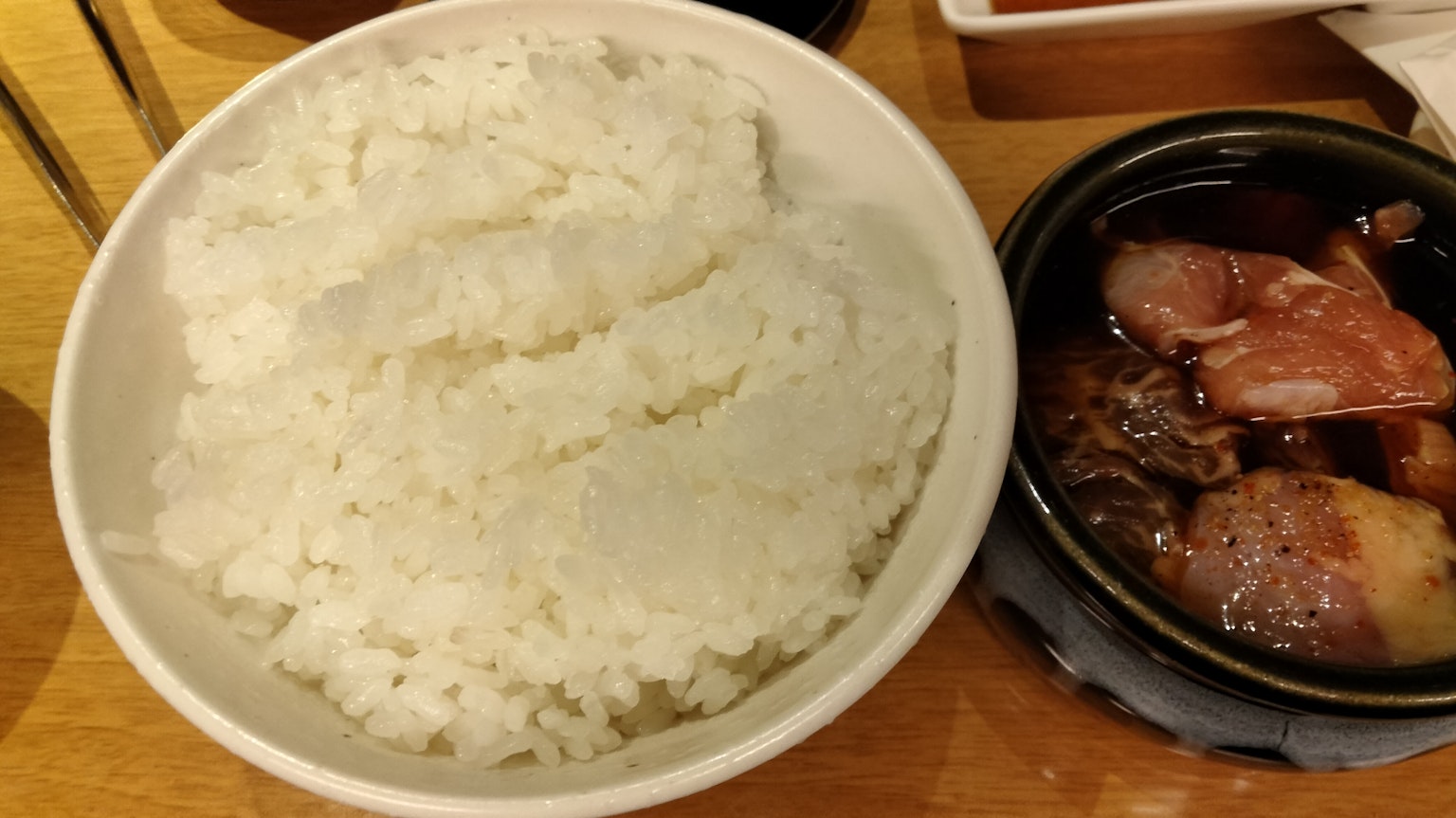 흰 쌀밥과 소스에 담긴 고기 요리 접시가 나란히 놓여 있다