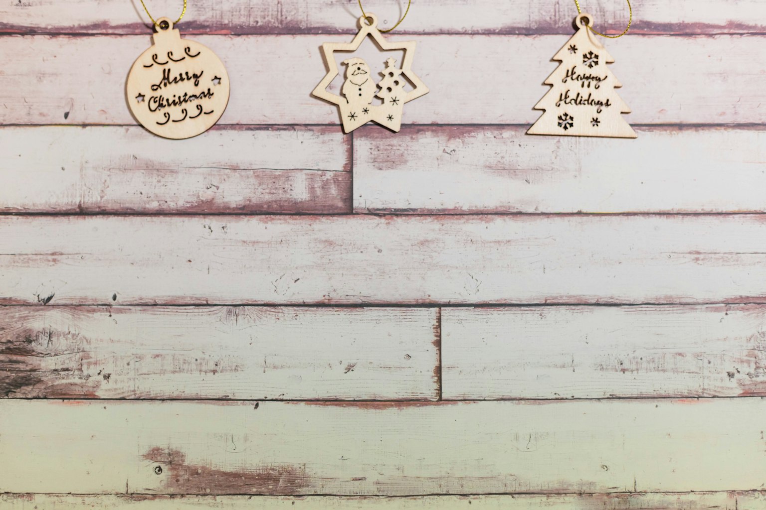 Decorazioni natalizie in legno appese a un muro di legno bianco