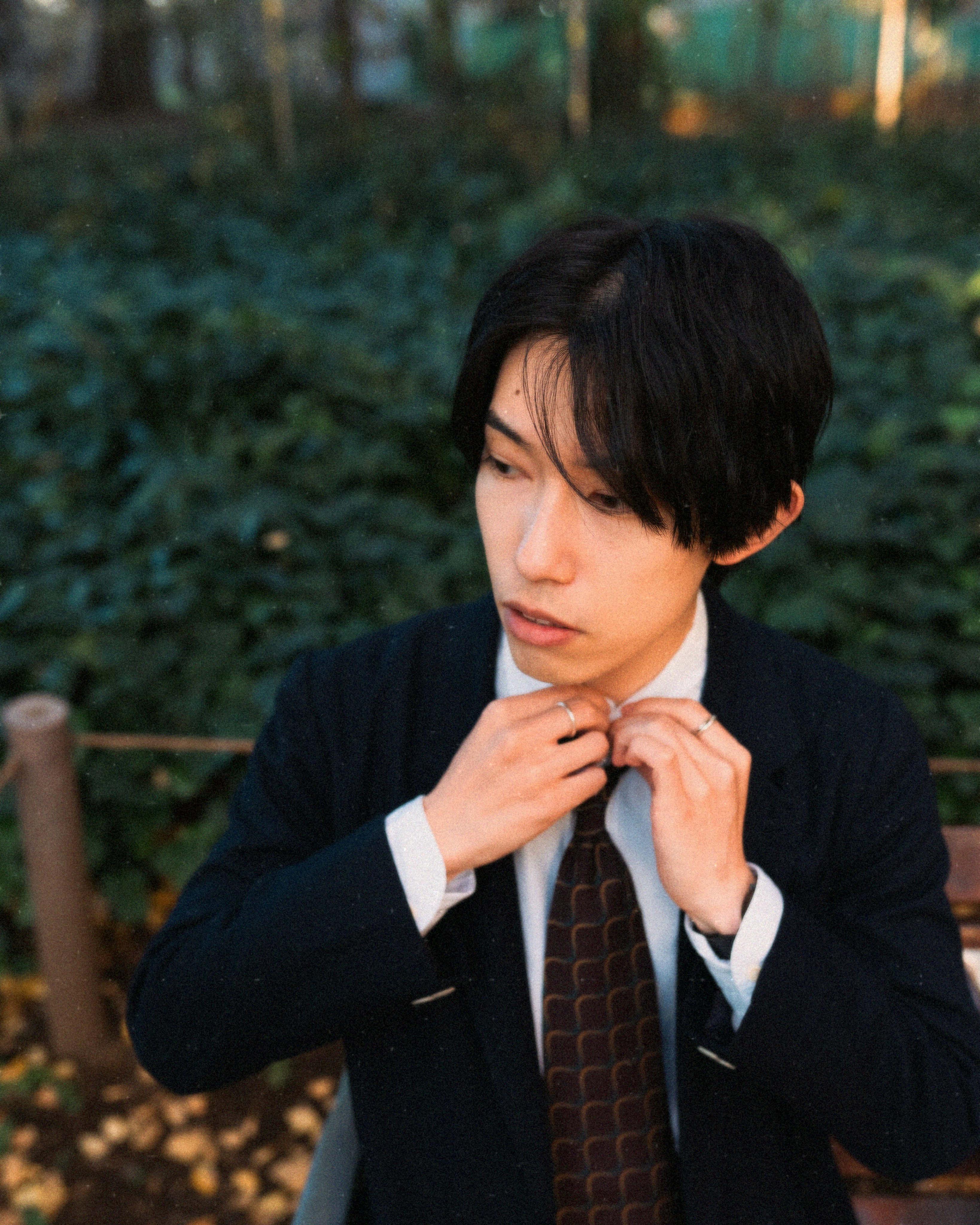 公園のベンチでネクタイを整える男性