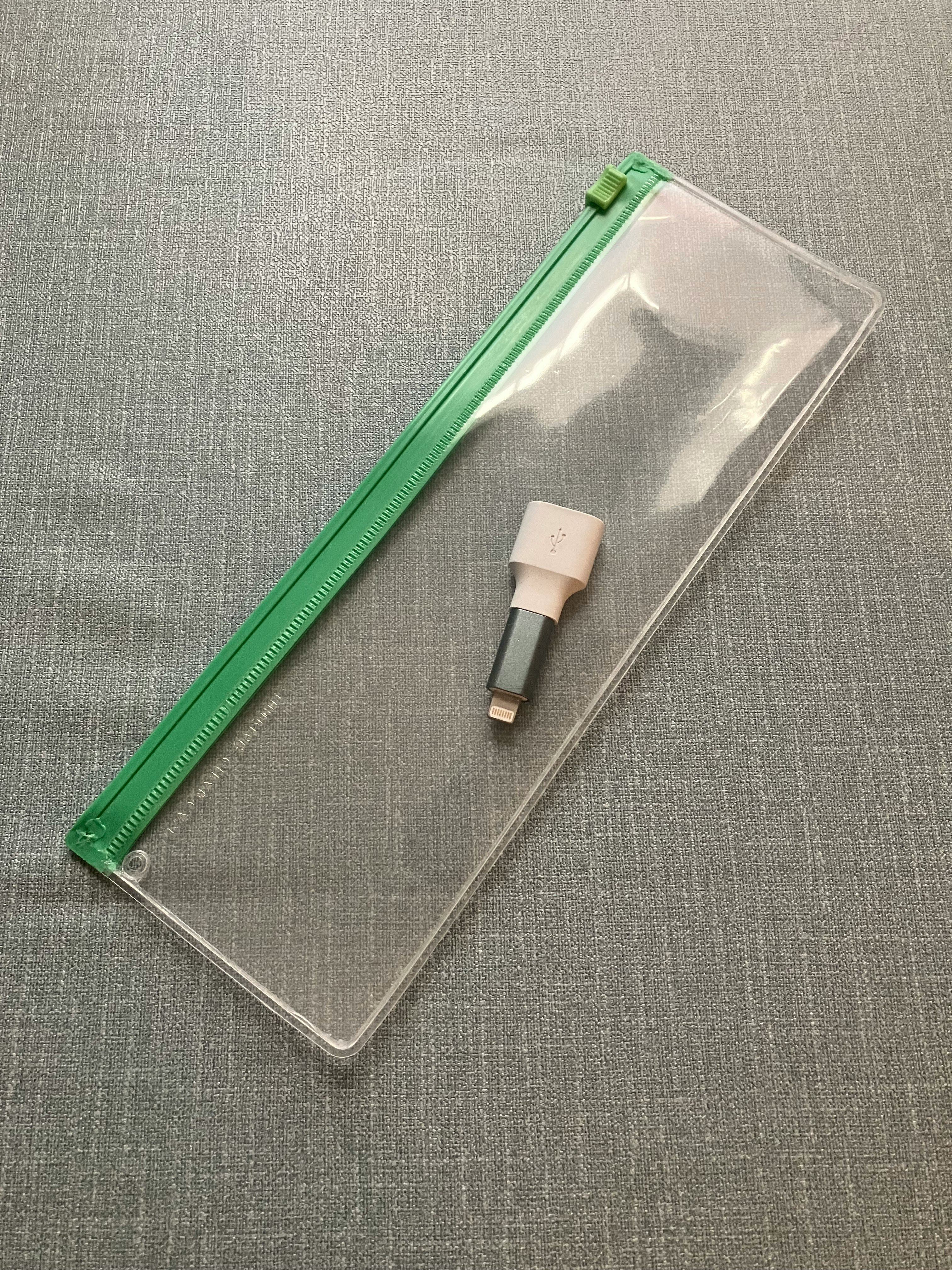 Penggaris hijau dan konektor kabel putih dalam casing bening di atas kain