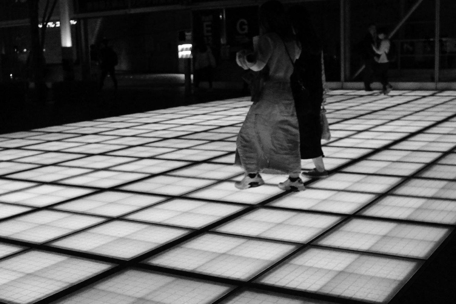 Two people dancing on a black and white illuminated floor