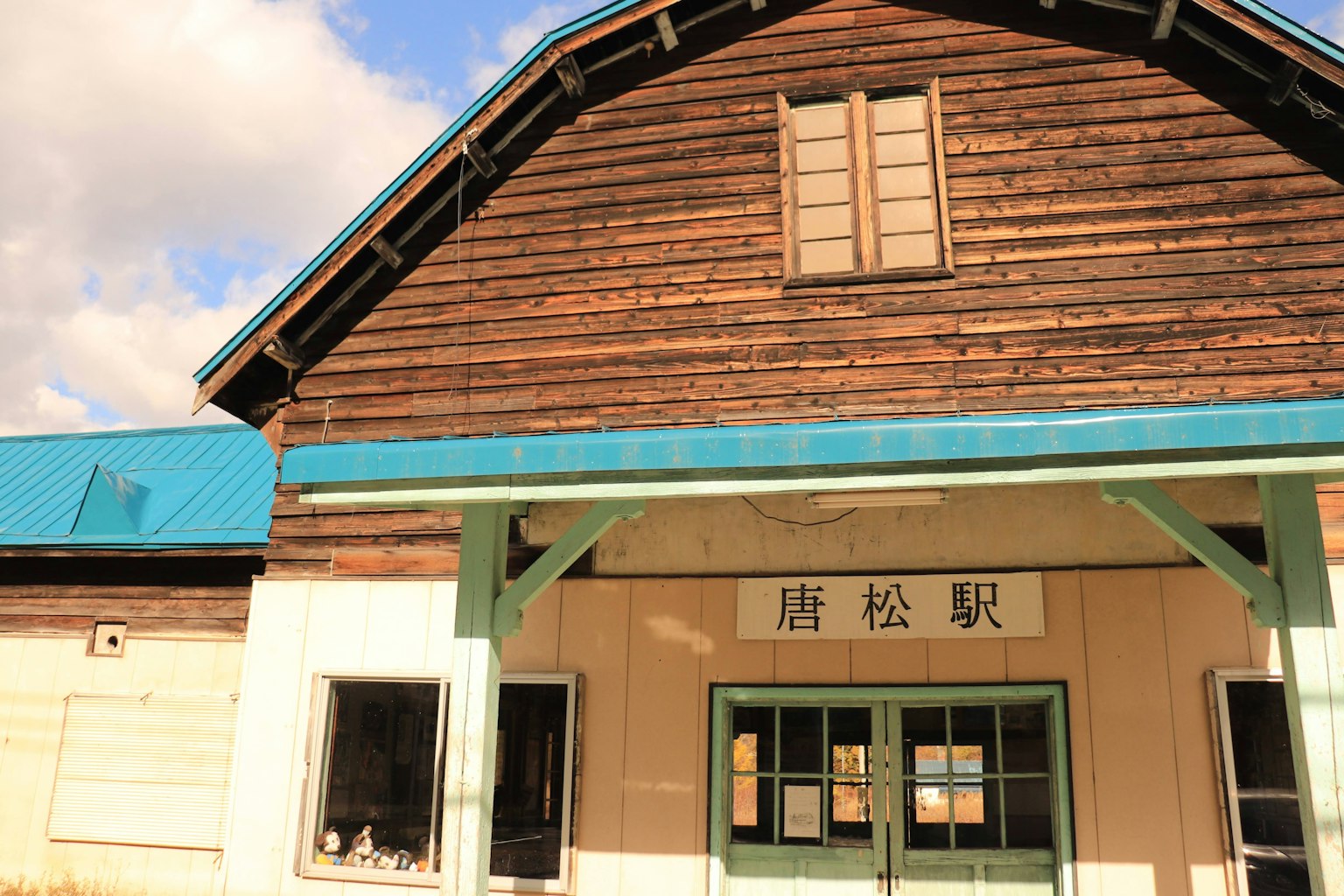 Esterno di una vecchia stazione ferroviaria in legno con finestre un tetto blu e pareti bianche