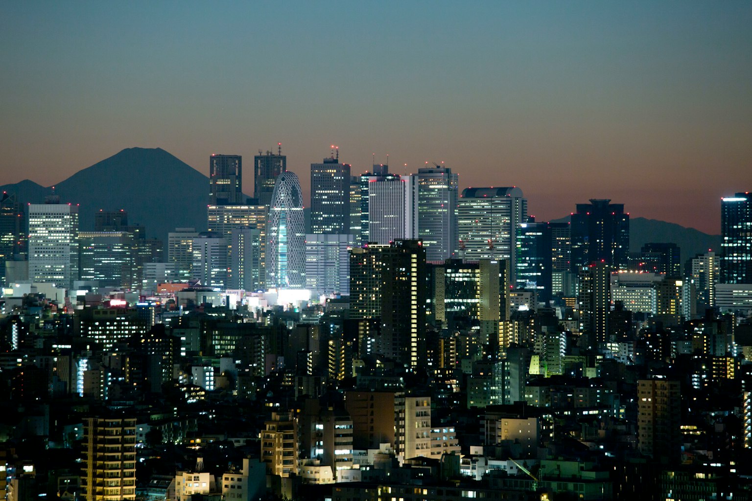 Khung cảnh đêm Tokyo với các tòa nhà chọc trời và bóng dáng núi