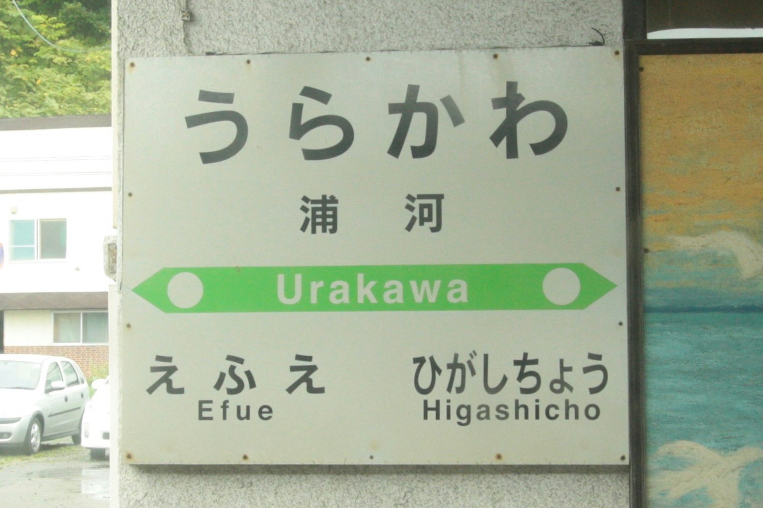 Insegna della stazione per Urakawa con frecce verdi che indicano le direzioni