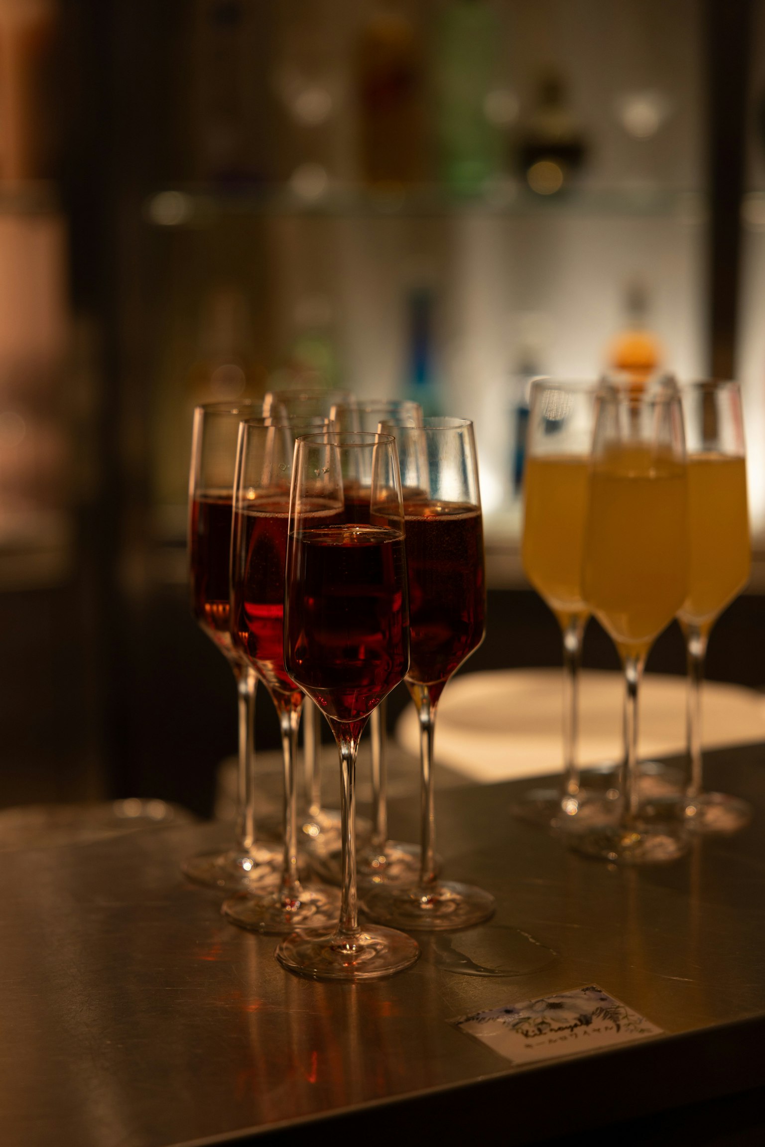 赤い飲み物が入ったグラスと黄色い飲み物が入ったグラスが並ぶバーのシーン