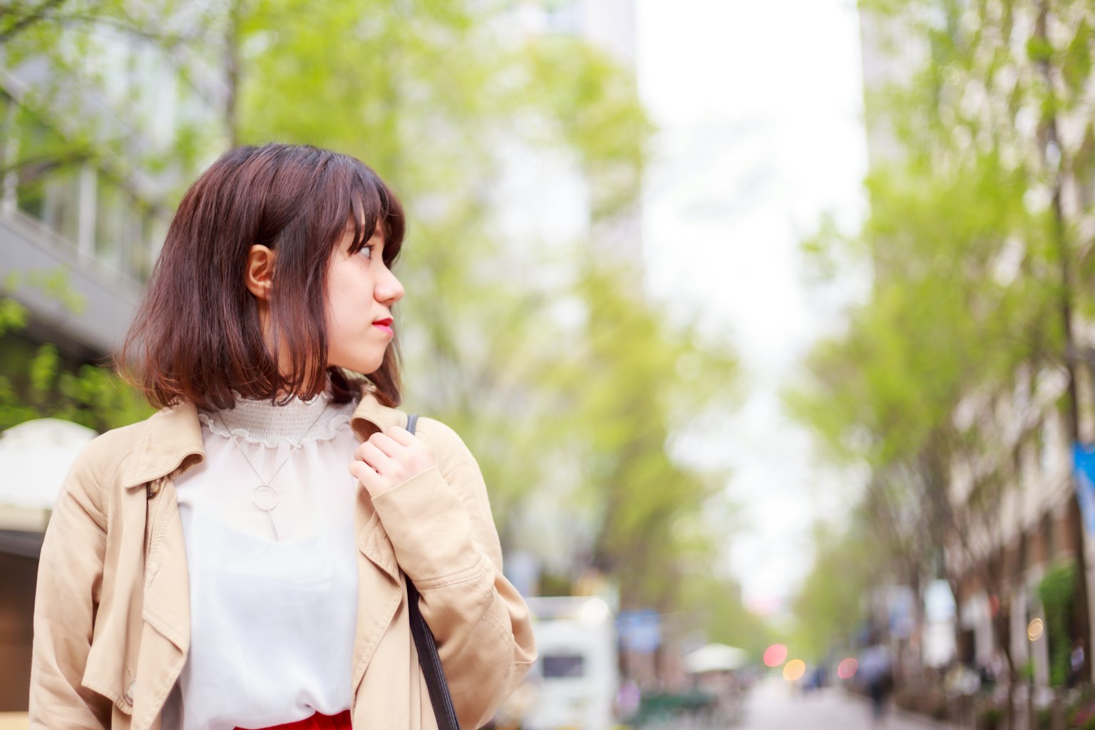 城市中回頭的女性肖像明亮的綠色樹木和城市背景