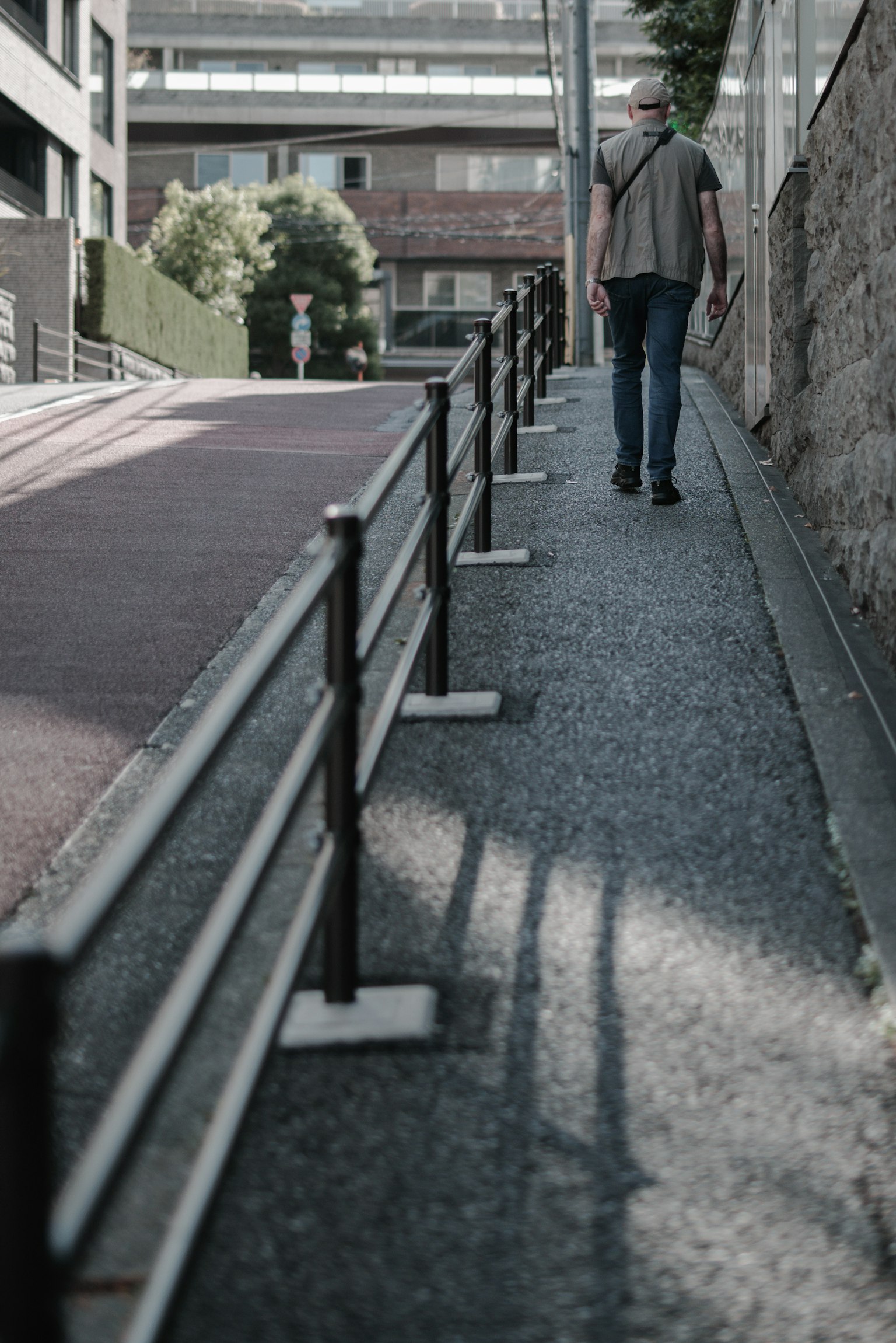 A person walking up a sloped path with railings in an urban setting