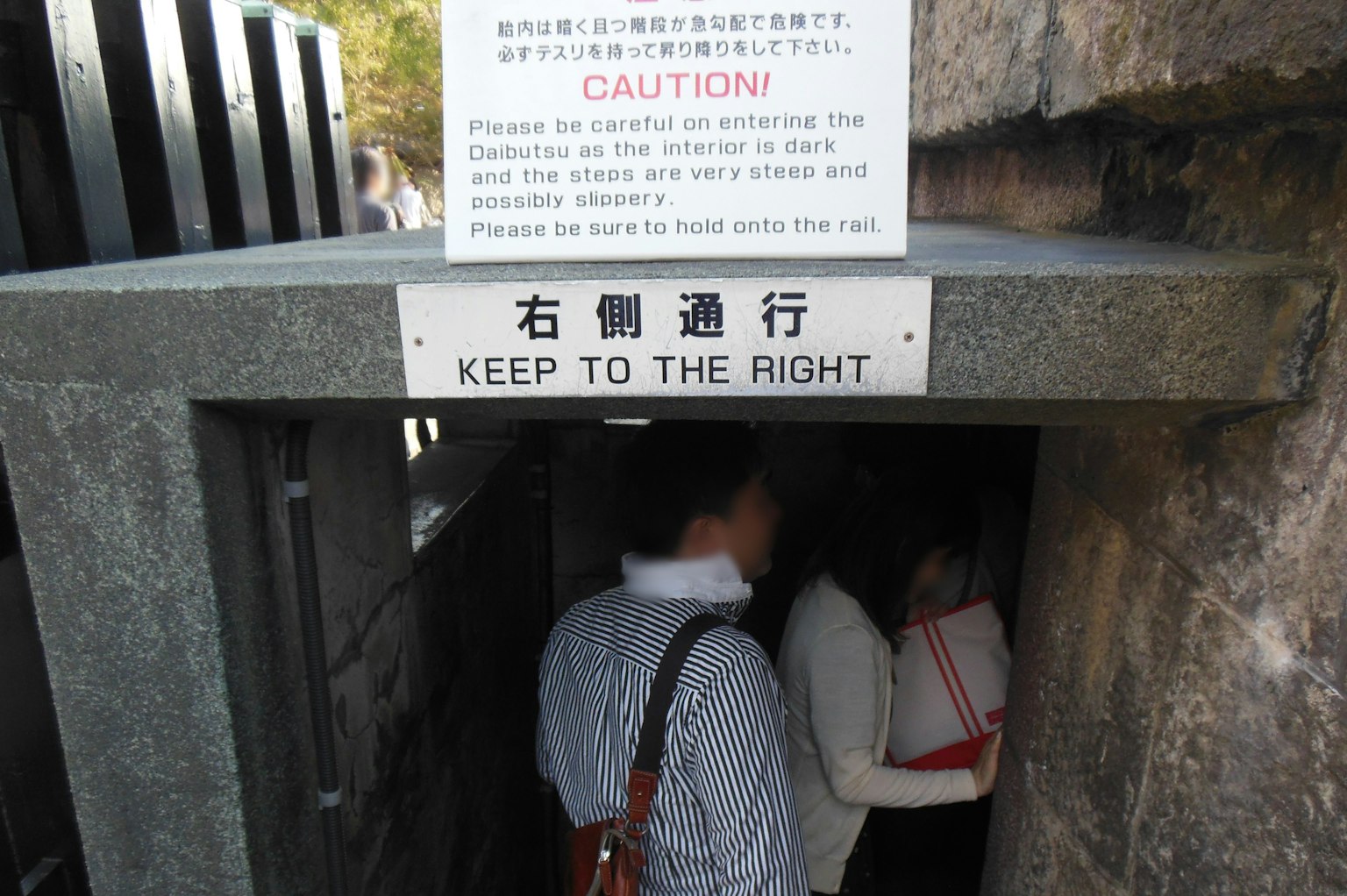 入口处的警告标志和通过狭窄通道的人们