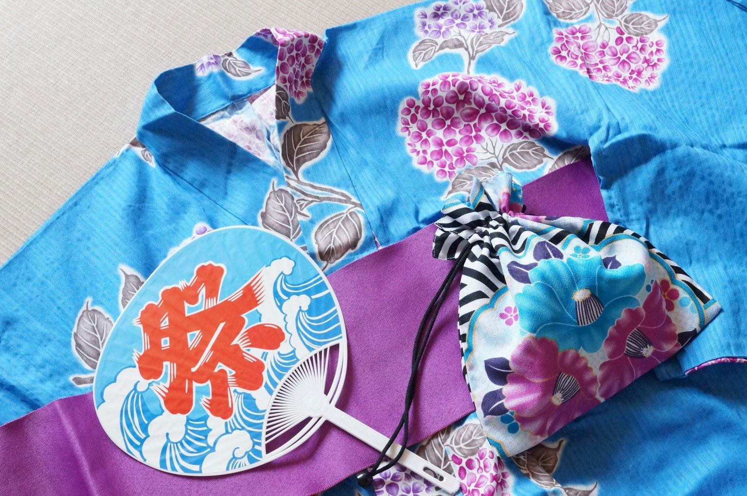 Yukata hoa màu xanh với quạt obi màu tím và phụ kiện tóc nhiều màu