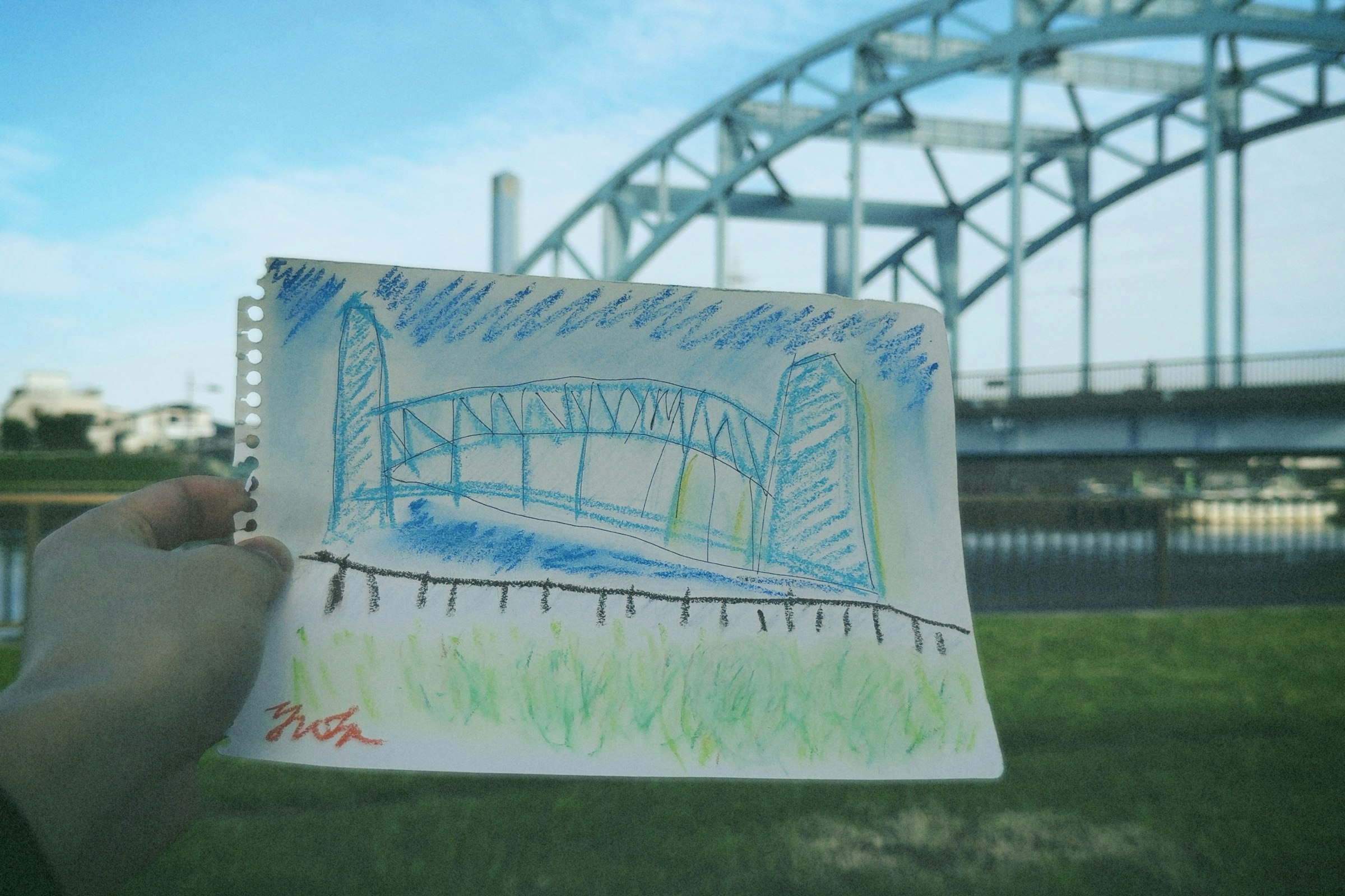 川沿いの河川敷で手に持たれたスケッチブックの絵