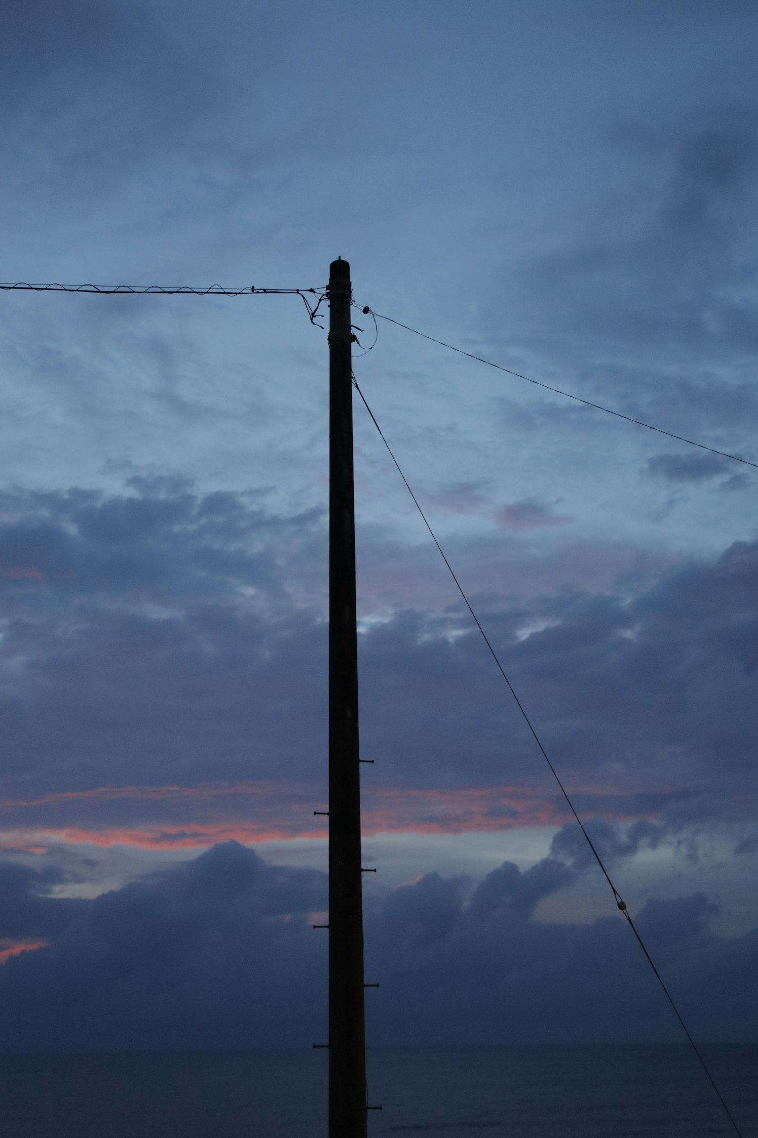 Tiang listrik dekat laut dengan langit senja yang indah