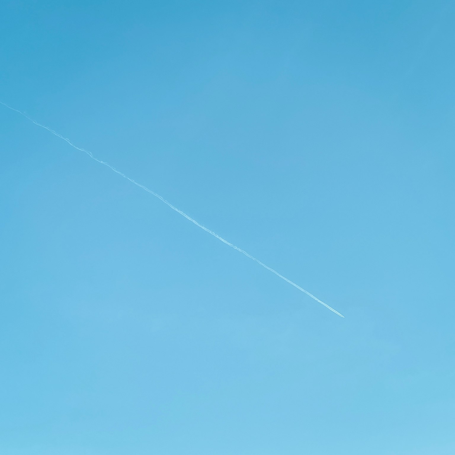 Un cielo azul claro con una estela blanca de avión