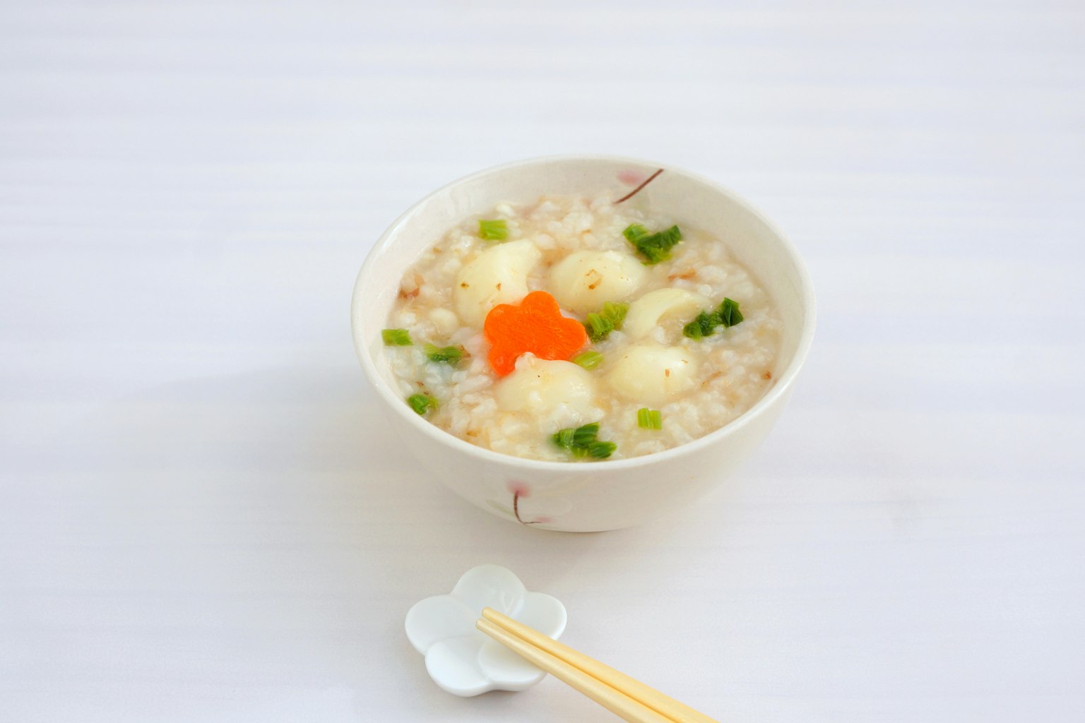 Ciotola di congee guarnita con carote e cipollotti
