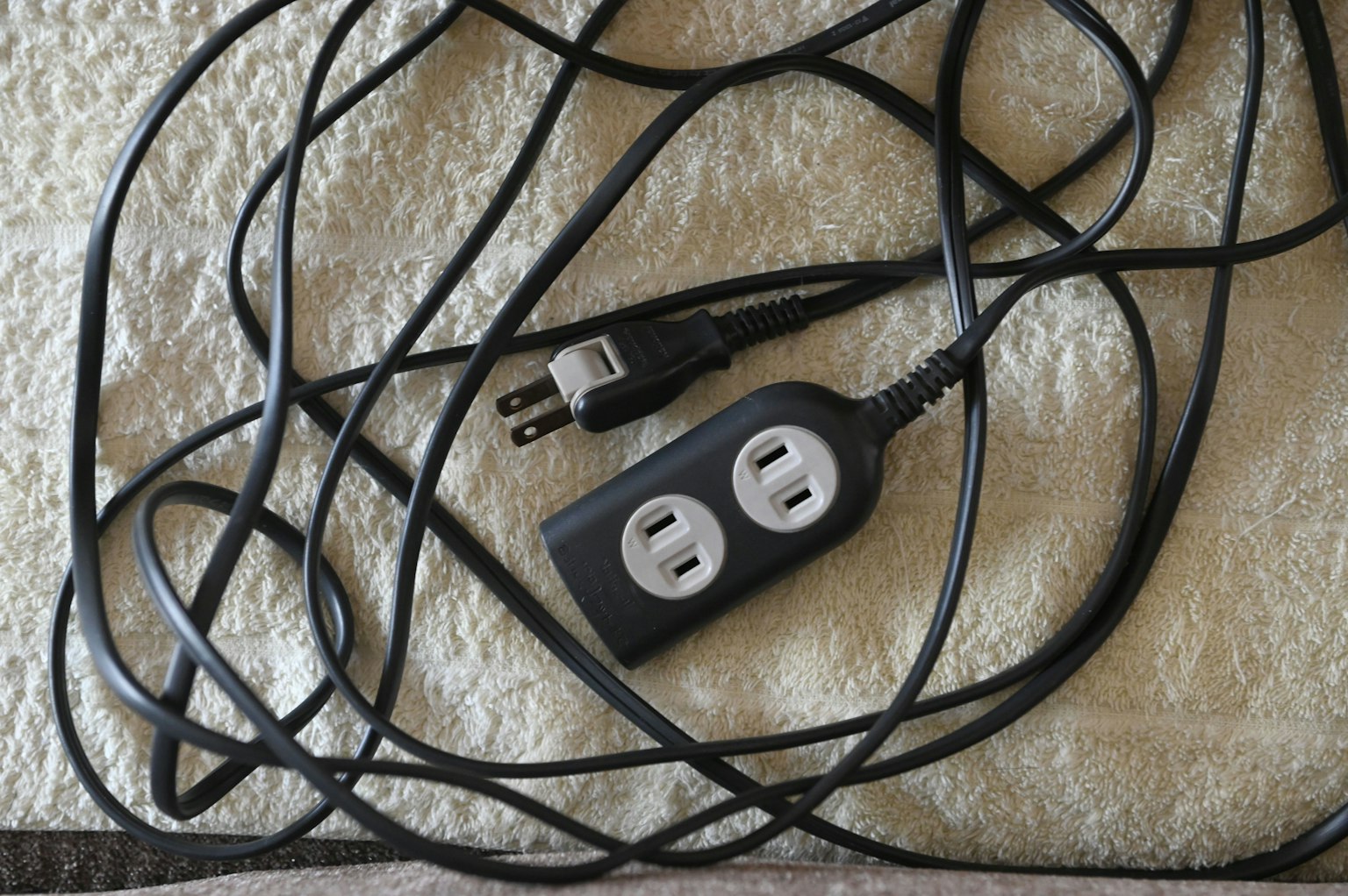 Kabel ekstensi hitam dengan kabel kusut di atas permukaan kain putih