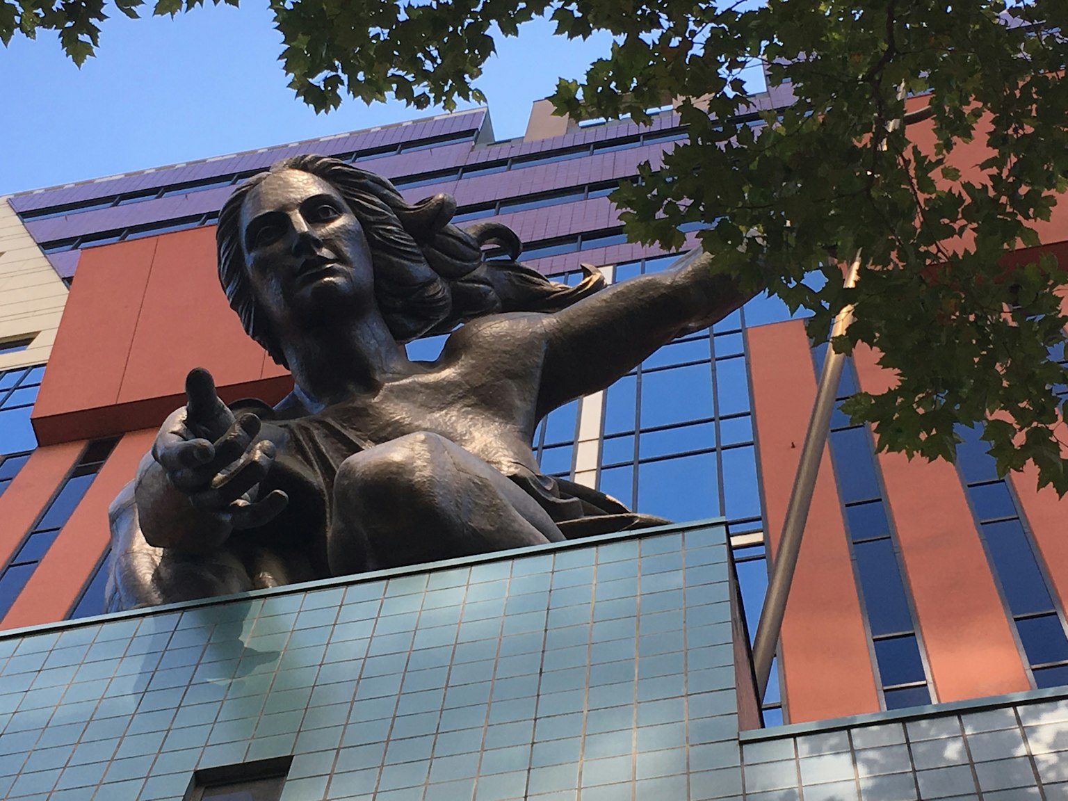 Große bronzestatue, die sich auf dem Dach eines Gebäudes ausstreckt
