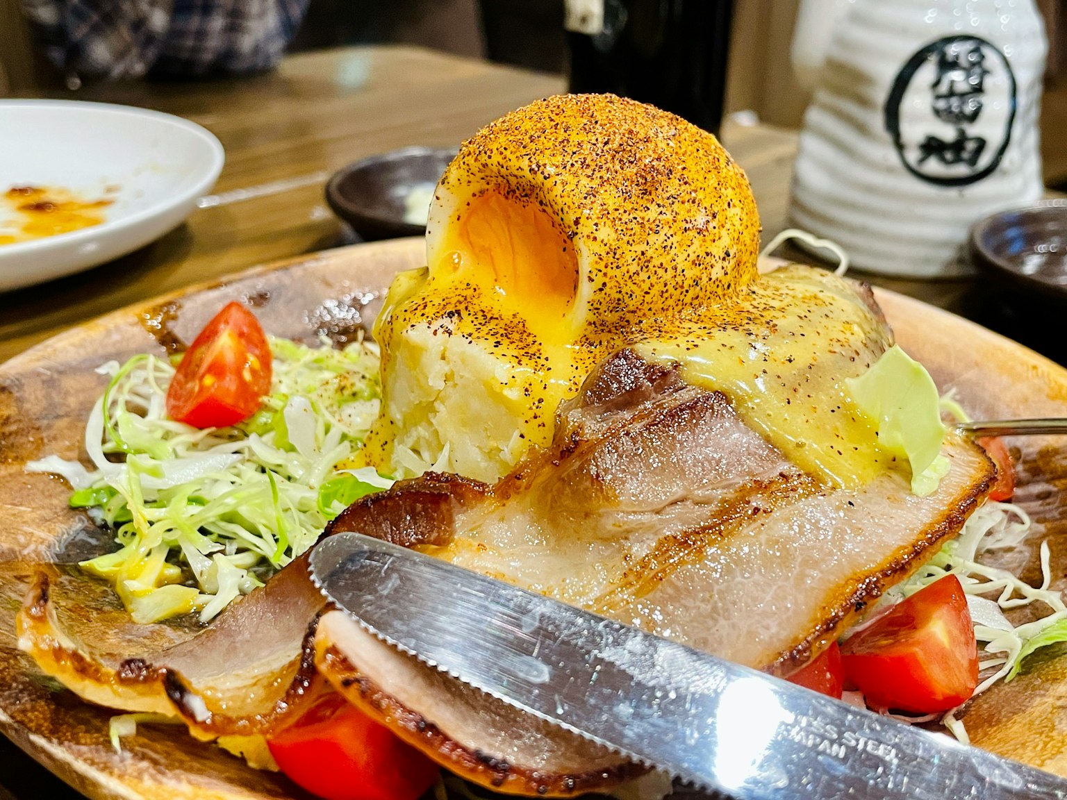 Dish featuring grilled pork with cabbage salad topped with a large piece of cheese