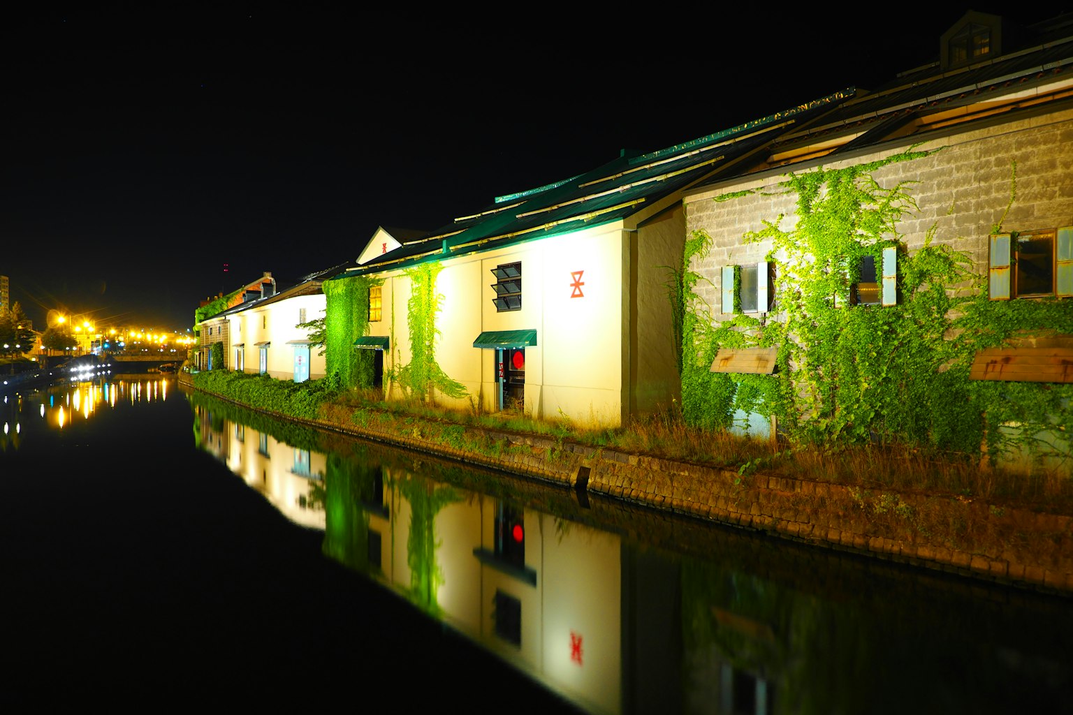 Hermosa escena nocturna de almacenes a lo largo del canal con reflejos en el agua