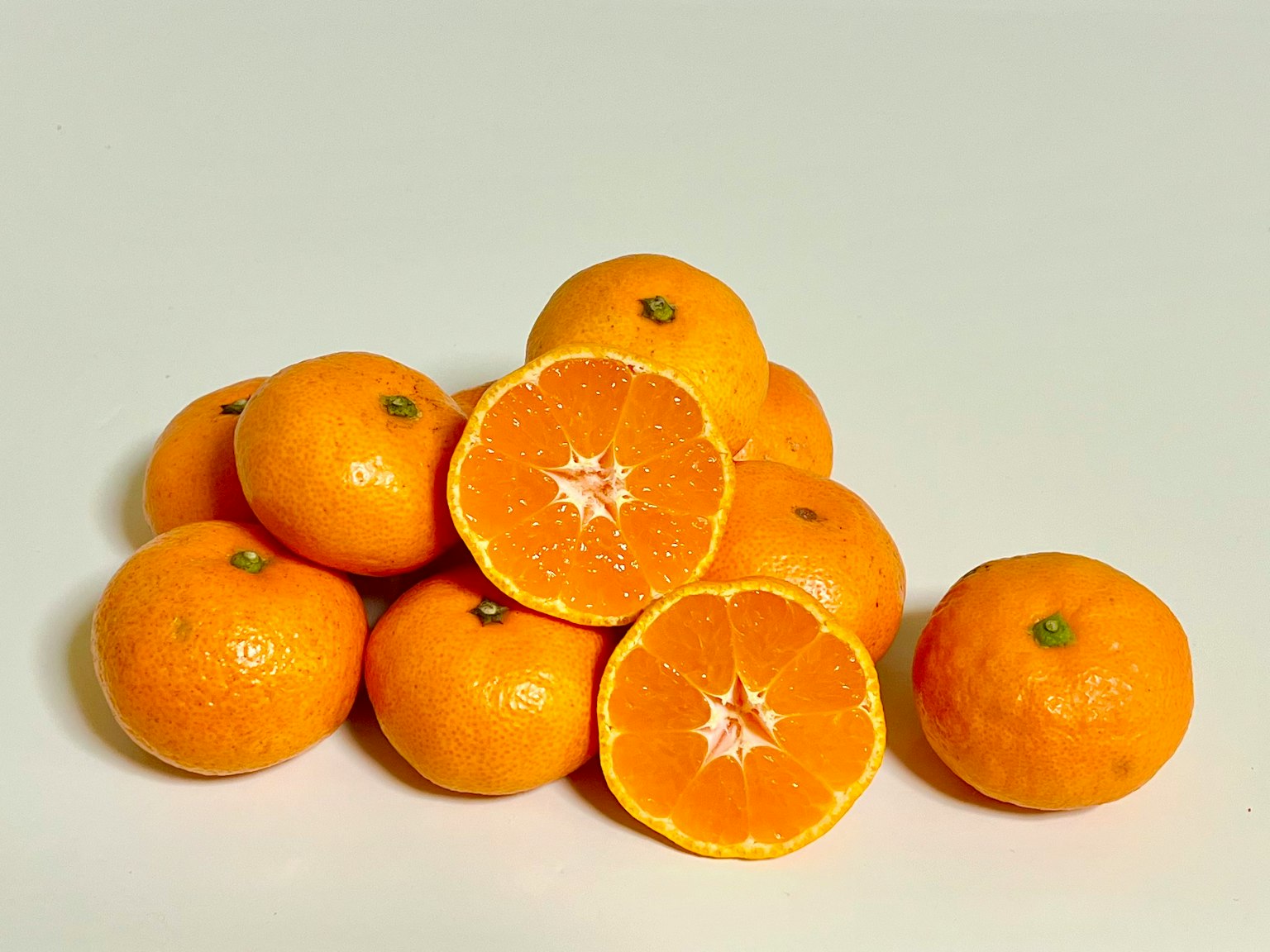 A pile of bright orange mandarins with one cut in half