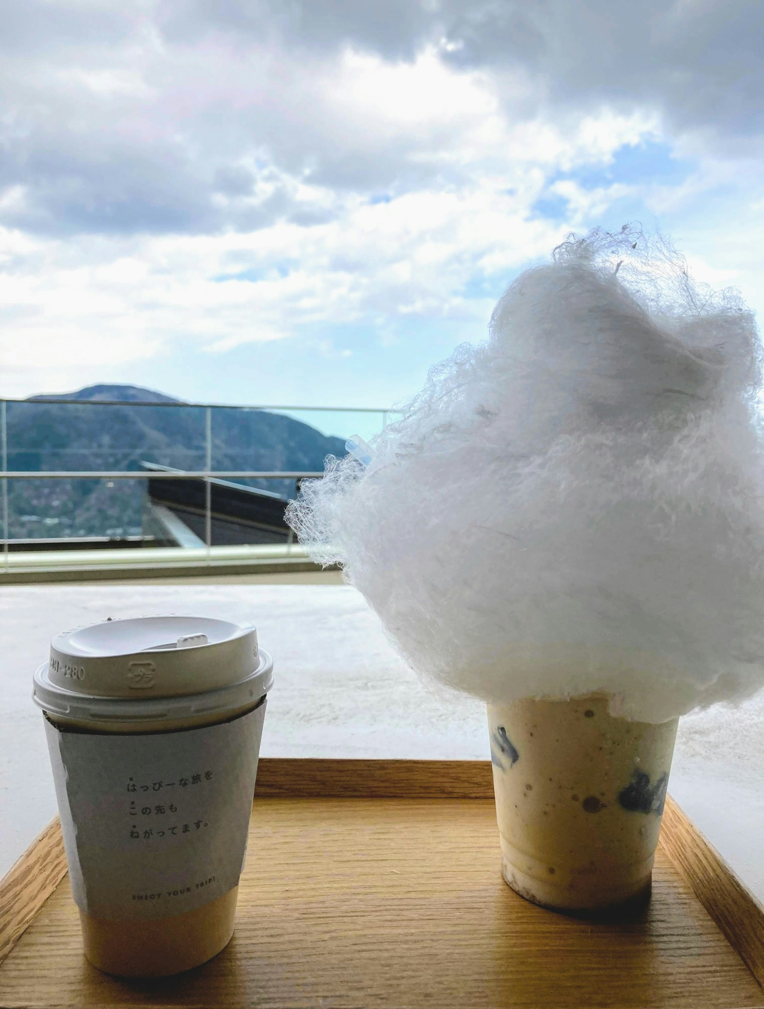 ถ้วยกาแฟและเครื่องดื่มที่มีฝอยน้ำตาลบนถาดไม้พร้อมวิวสวย