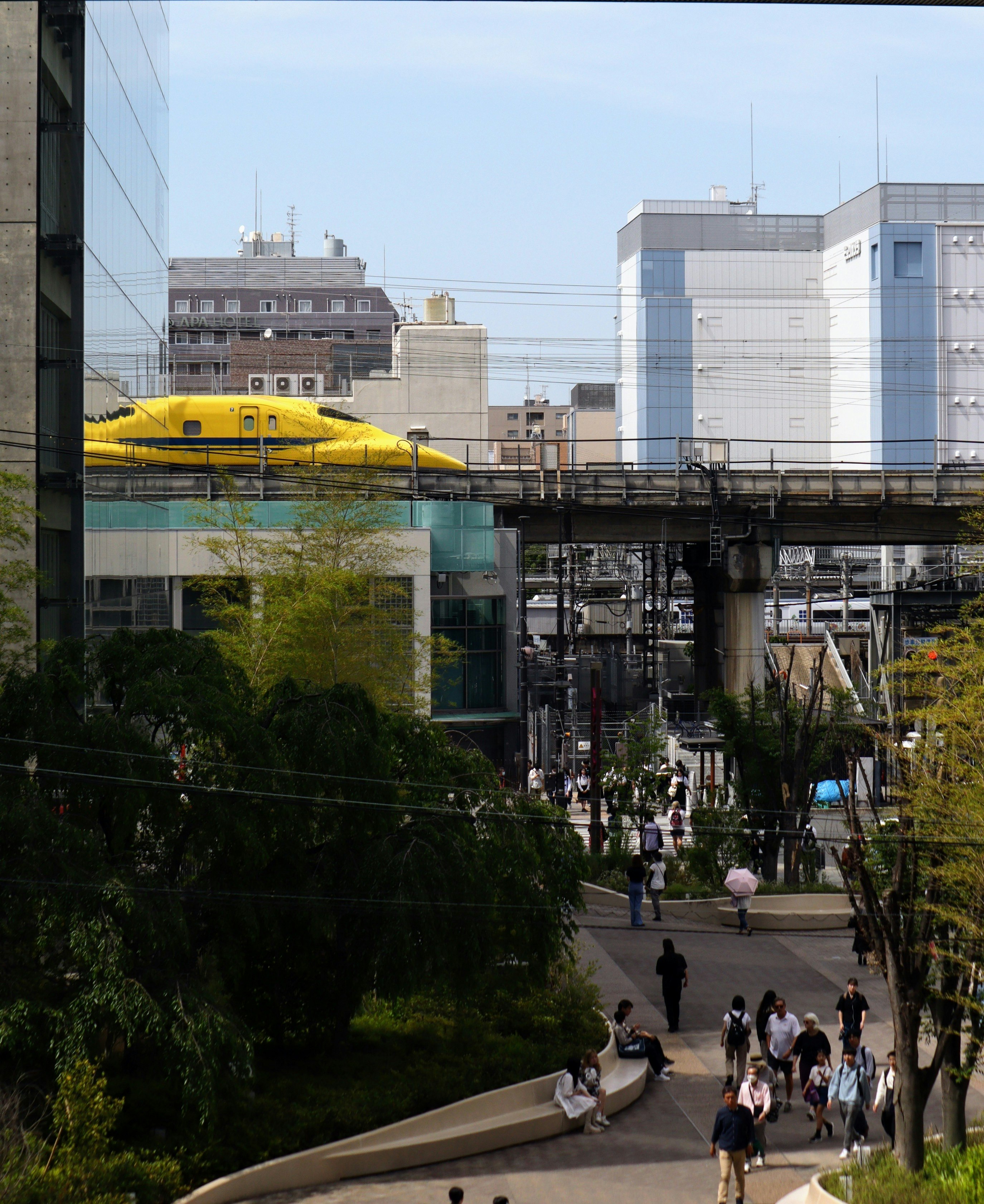 高架線路を走るドクターイエローの新幹線と駅前の街並み