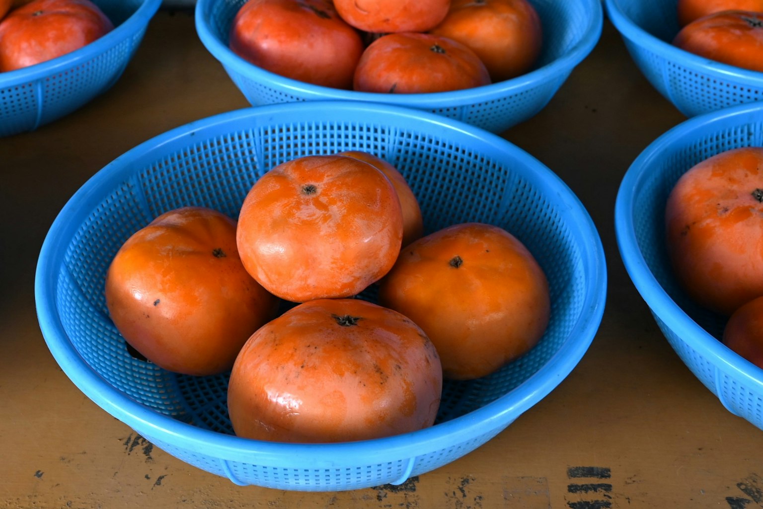 Kakis dans des paniers bleus sur une table de marché