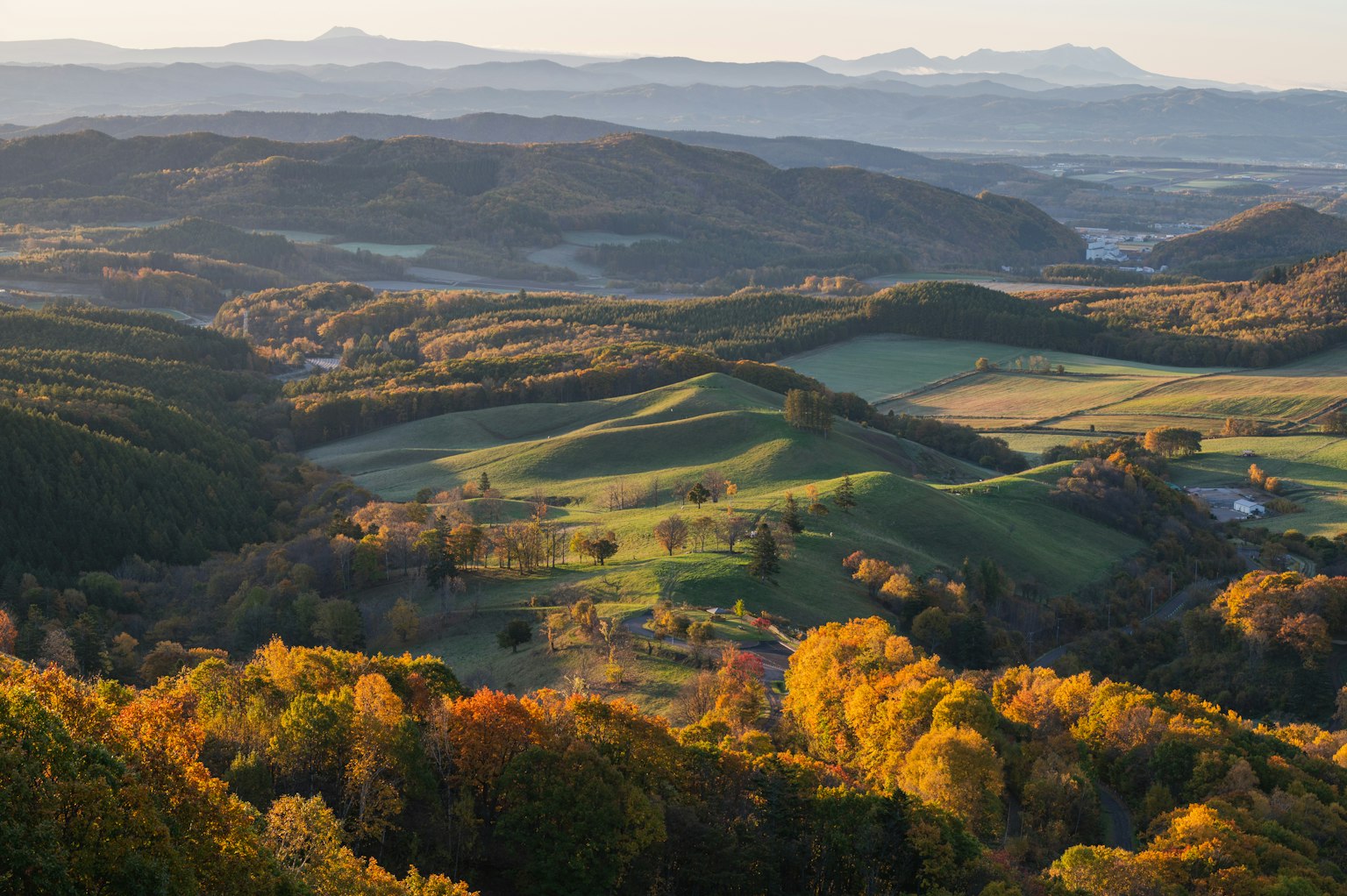 Vista escénica de colinas onduladas en colores de otoño con montañas distantes y valles