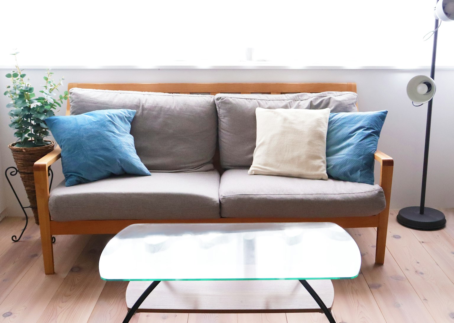 Sala simple con sofá de madera y cojines azules y beige