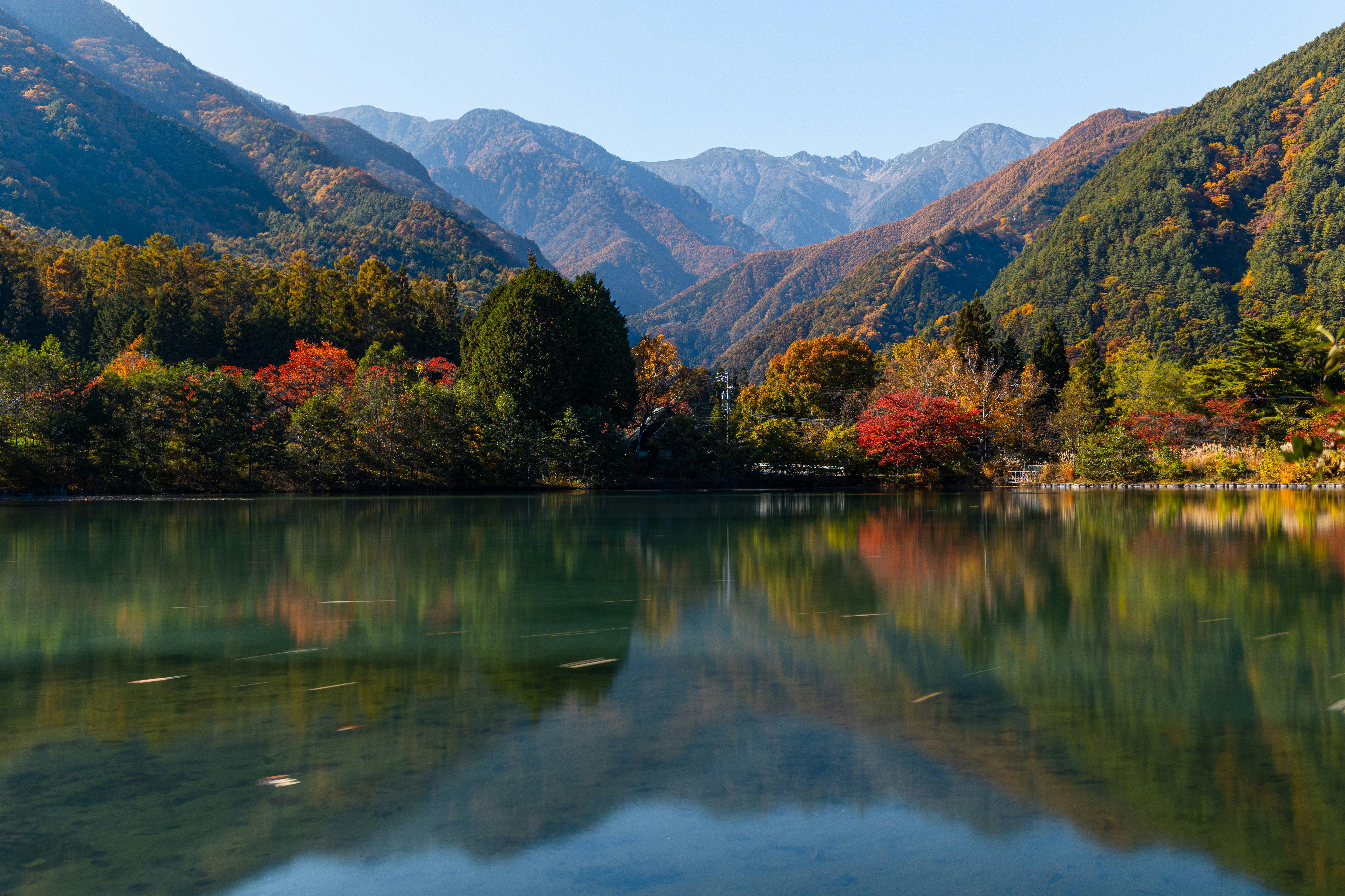 山々に囲まれた湖畔の静かな水面と紅葉