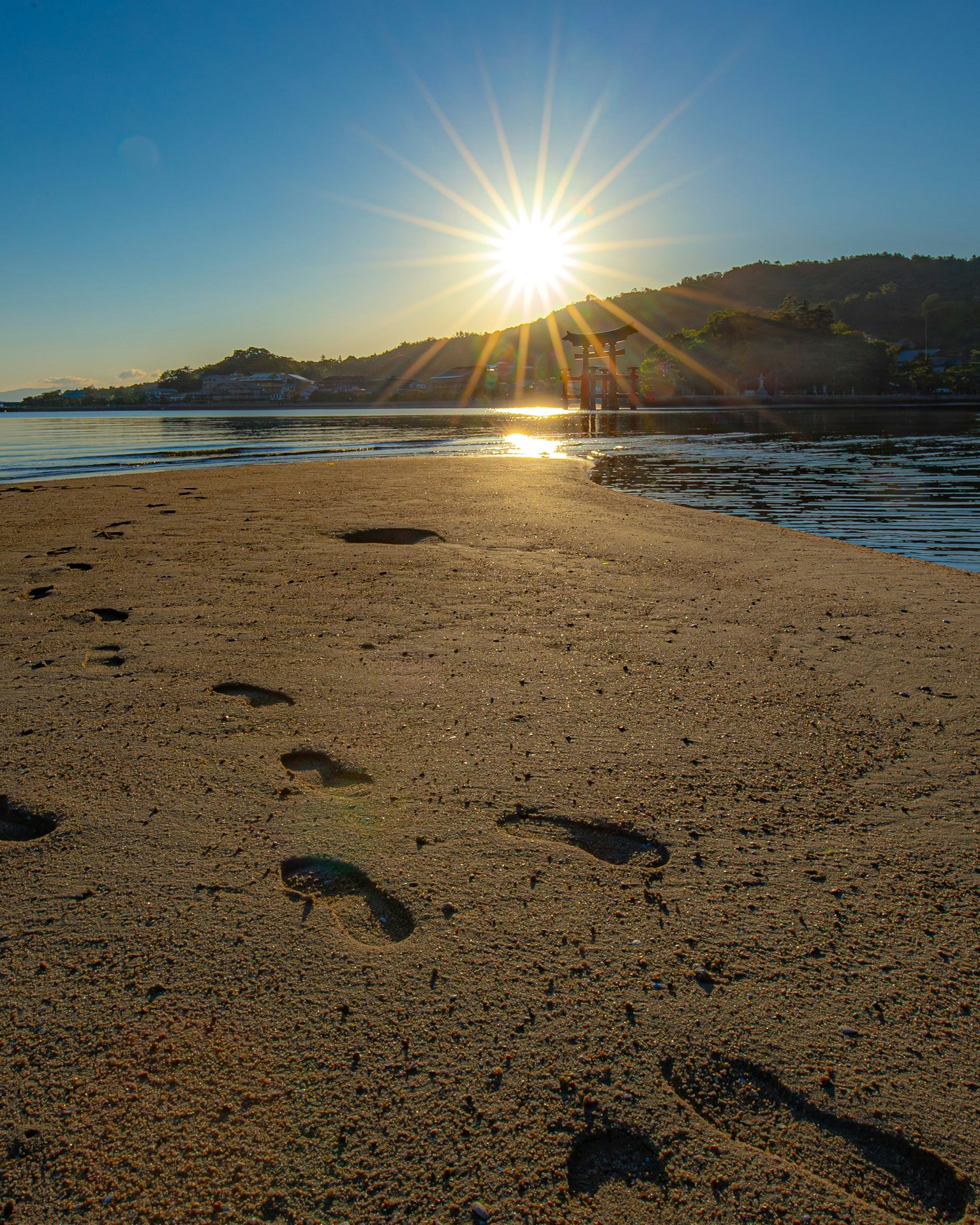 Orme sulla spiaggia sabbiosa con un sole che sorge