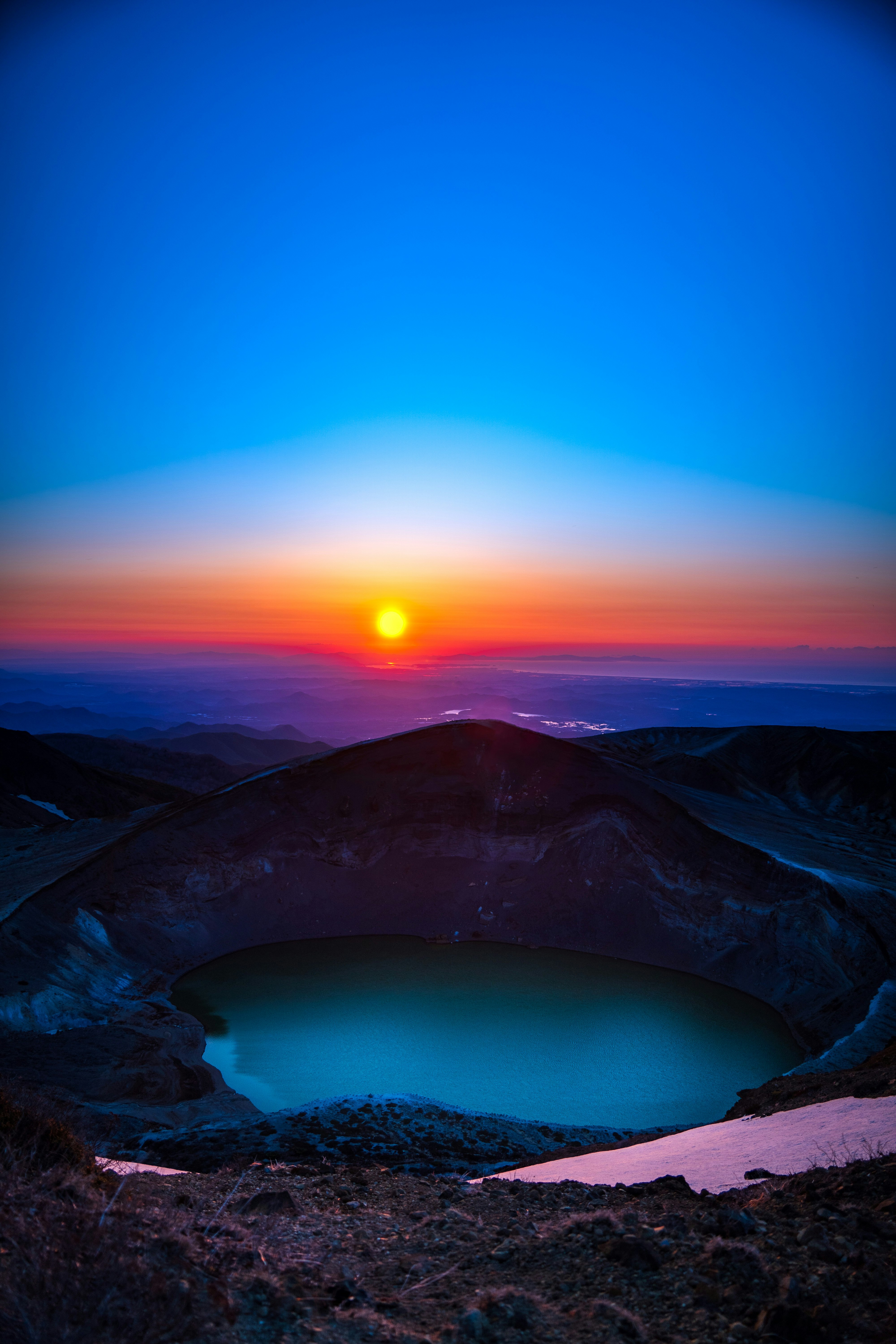 青い空とオレンジ色の夕日が美しい火山のクレーターの景色