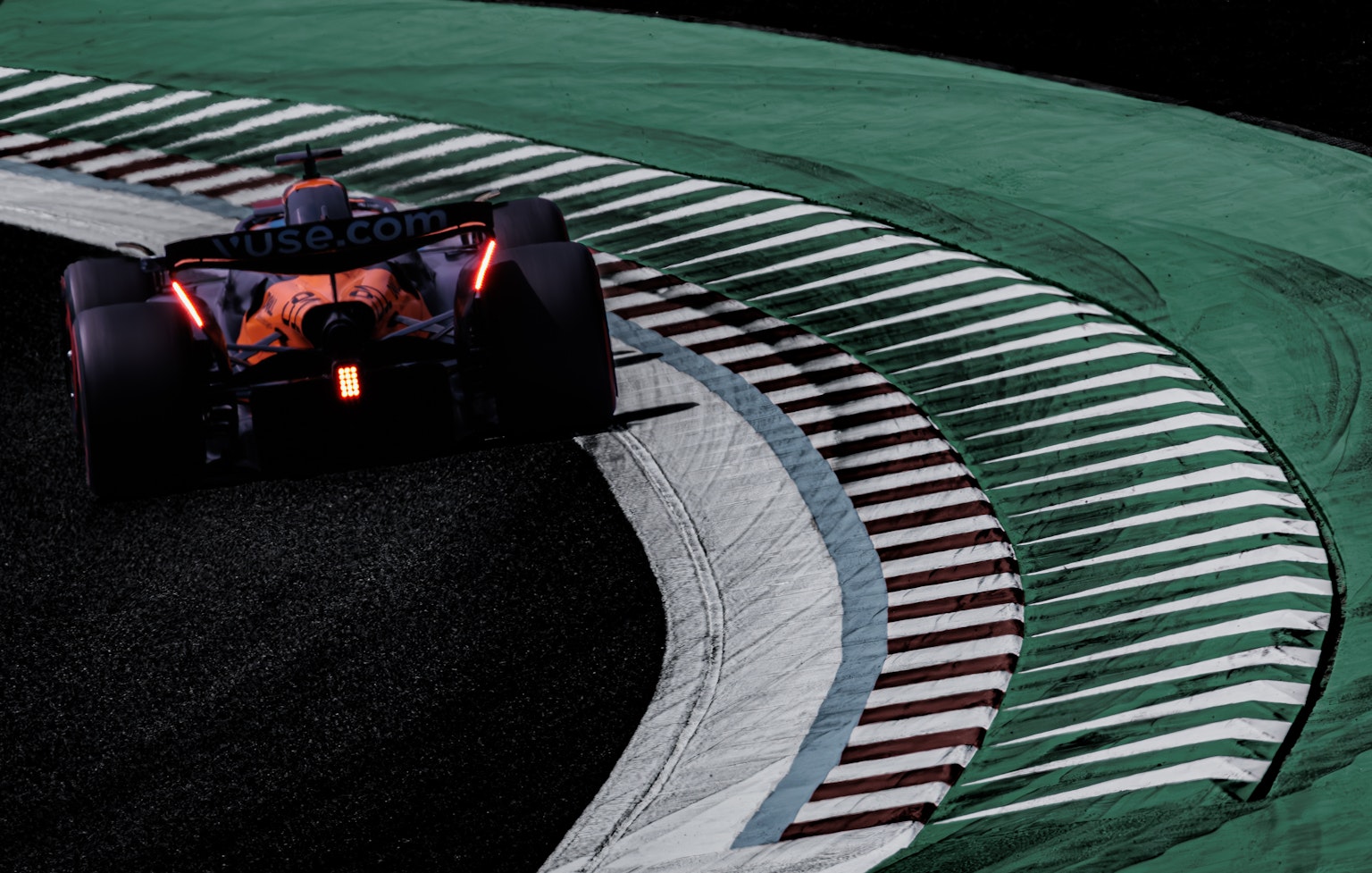 F1 자동차가 코너를 돌고 있는 장면 녹색 경계석과 흰색 줄무늬가 있는 트랙