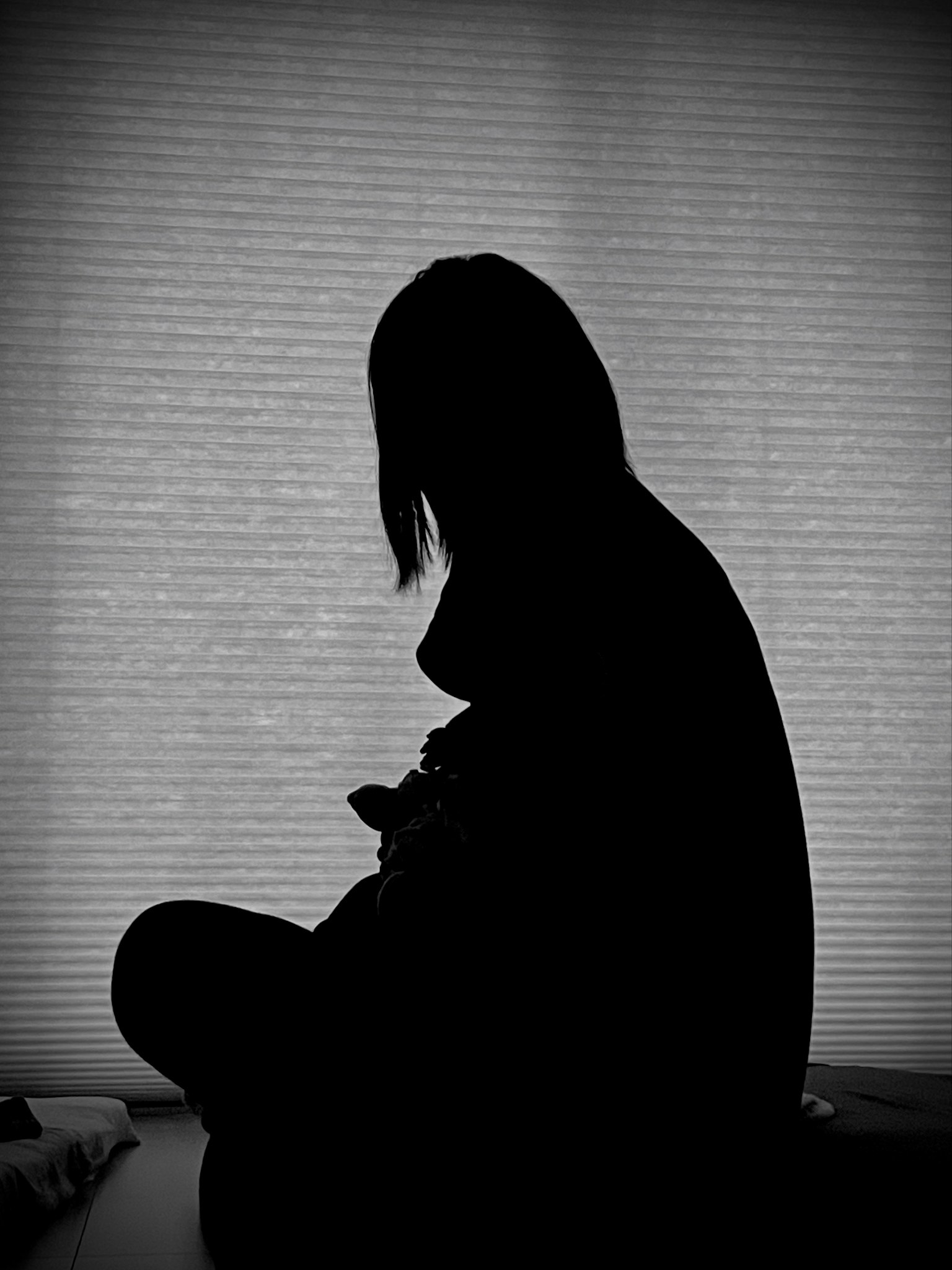 Silhouette d'une femme assise avec de la lumière provenant d'une fenêtre en arrière-plan