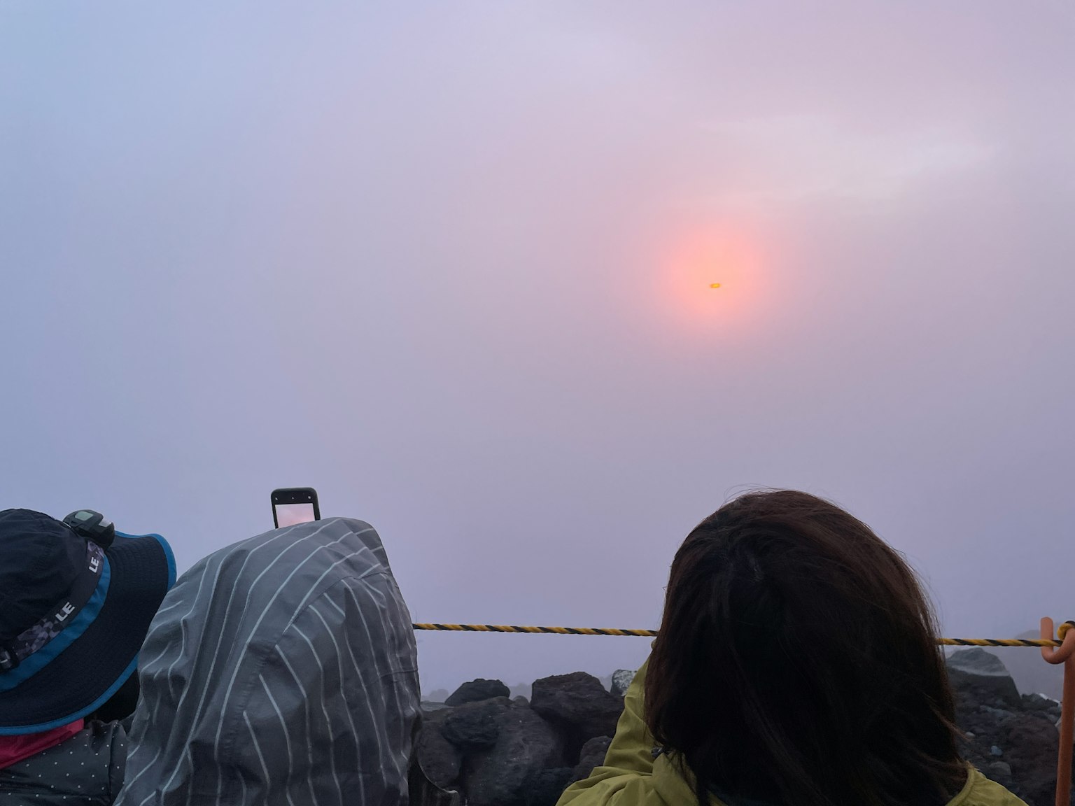 People observing the sunset emerging from fog