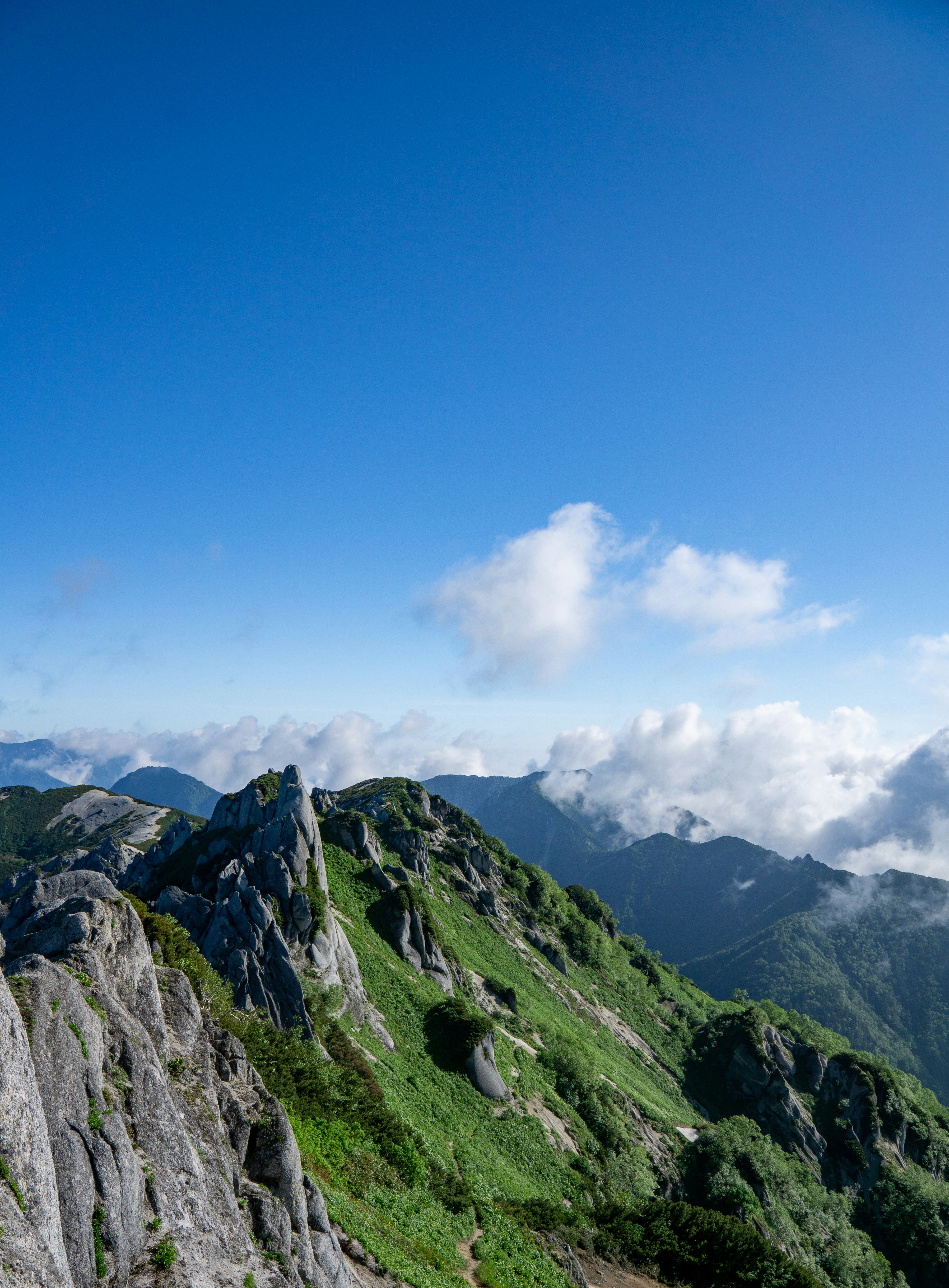 青空與雲彩下的郁郁蔥蔥的山脈風景