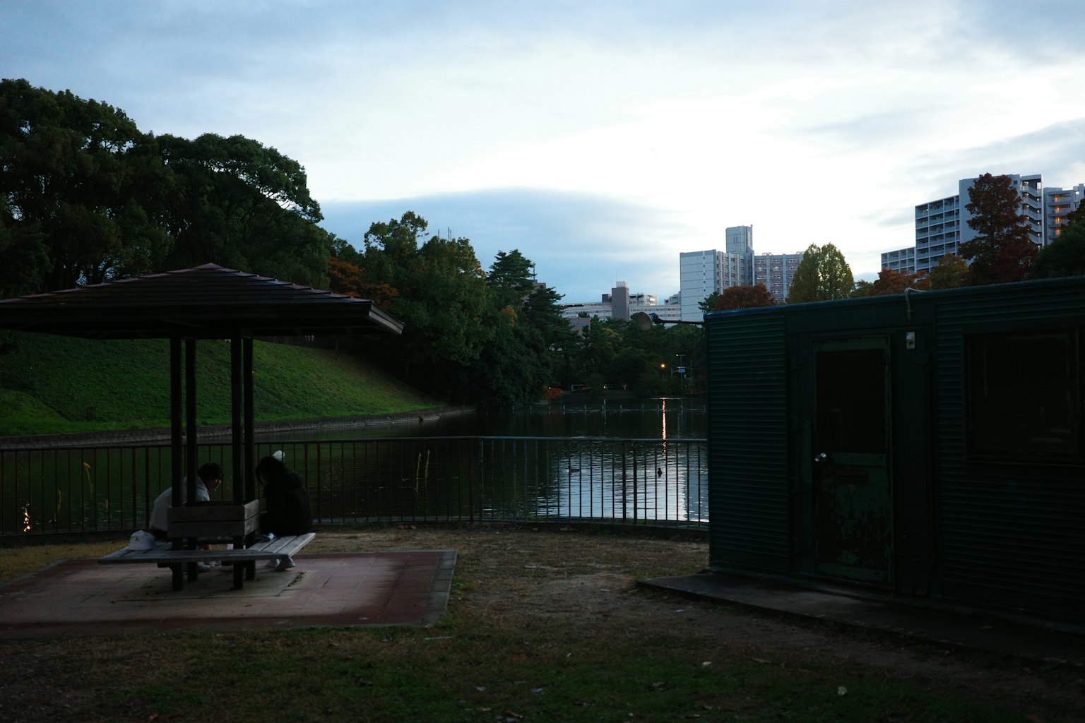 A view of a pavilion and bench near a park pond