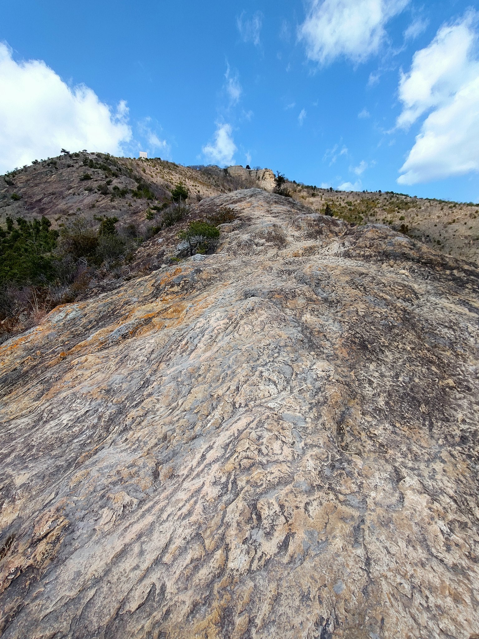 Smooth rocky slope under a blue sky with clouds