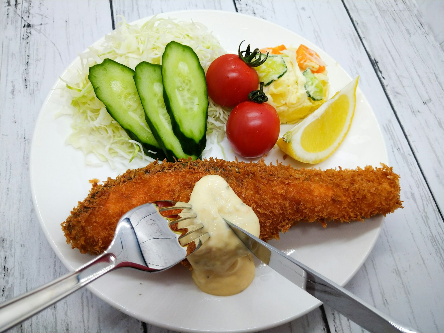 Paniertes Fischfilet mit Salat und Gemüse auf einem Teller