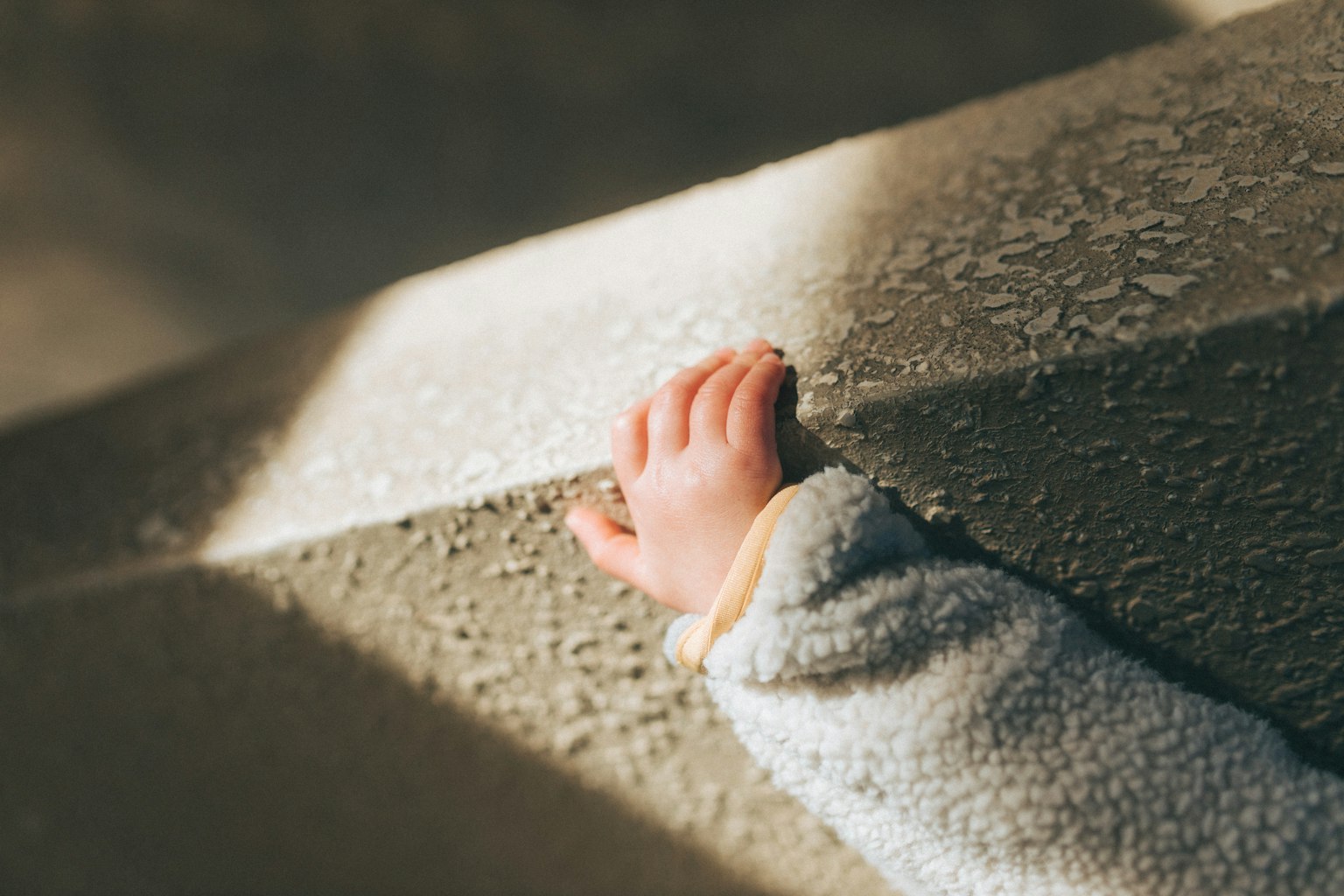 Gros plan d'une petite main agrippant une rampe d'escalier texturée