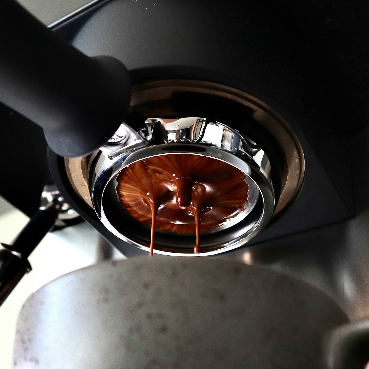 Rich espresso pouring from the portafilter of an espresso machine