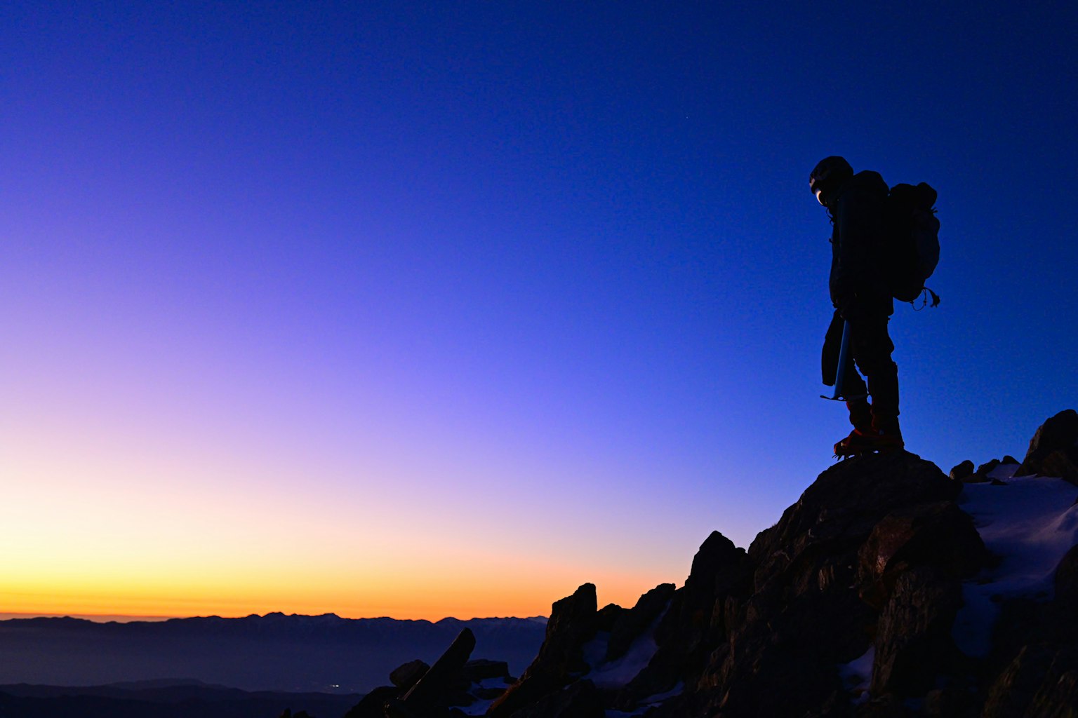 Siluet pendaki yang berdiri di puncak gunung langit gradasi dari biru ke ungu