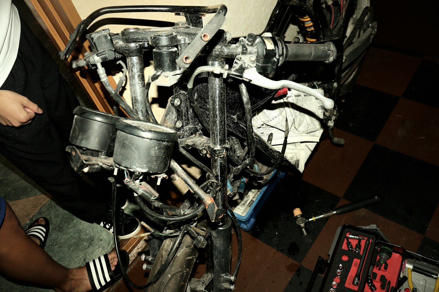 Foto eines demontierten Motorradmotors mit verschiedenen Teilen und Werkzeugen