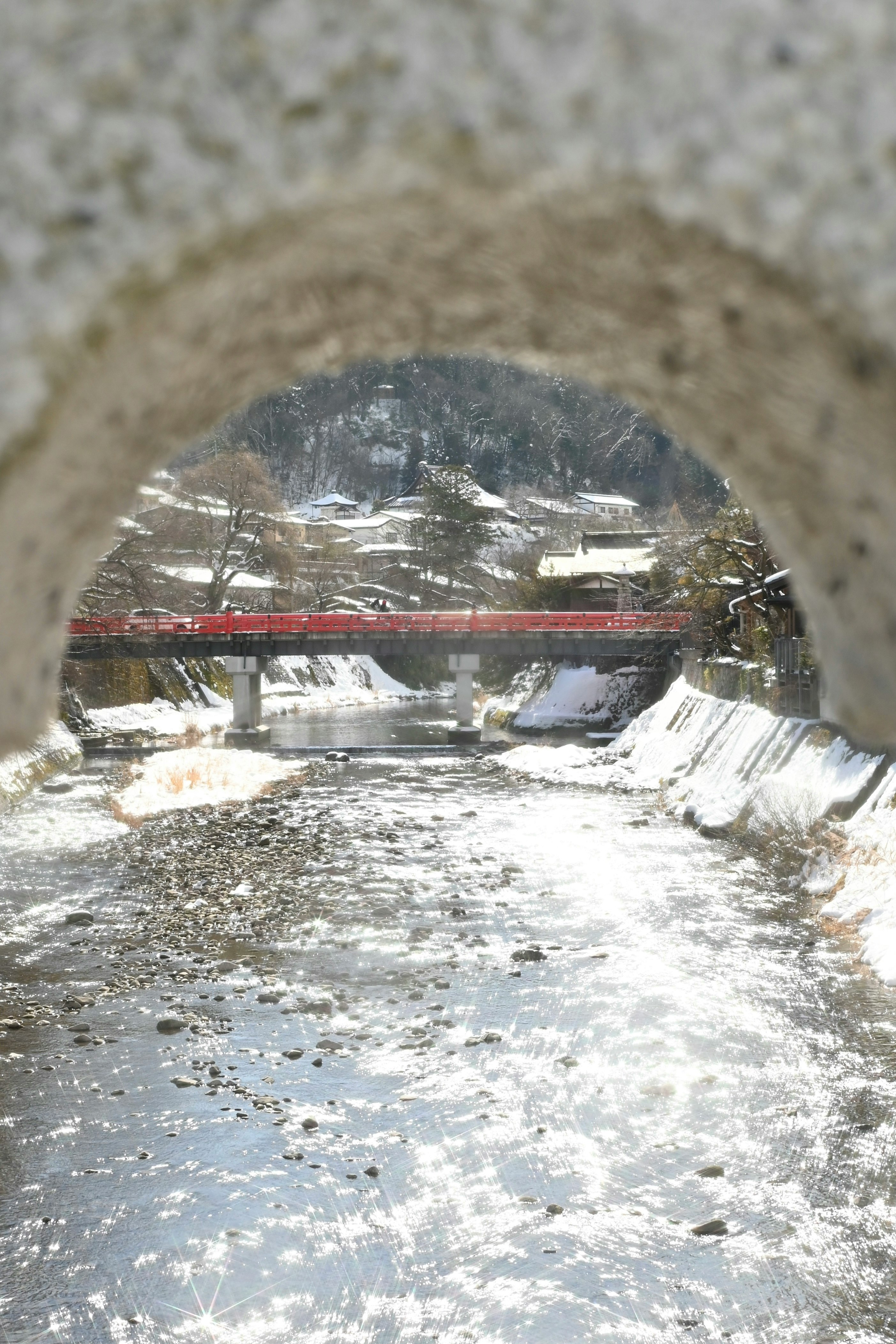 Red railway bridge seen through a snowy tunnel
