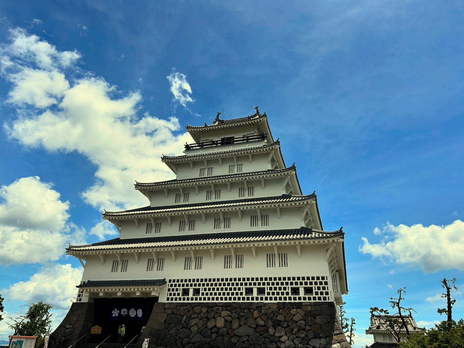 Una estructura de castillo blanco que se eleva bajo un cielo azul con intrincadas decoraciones en el tejado