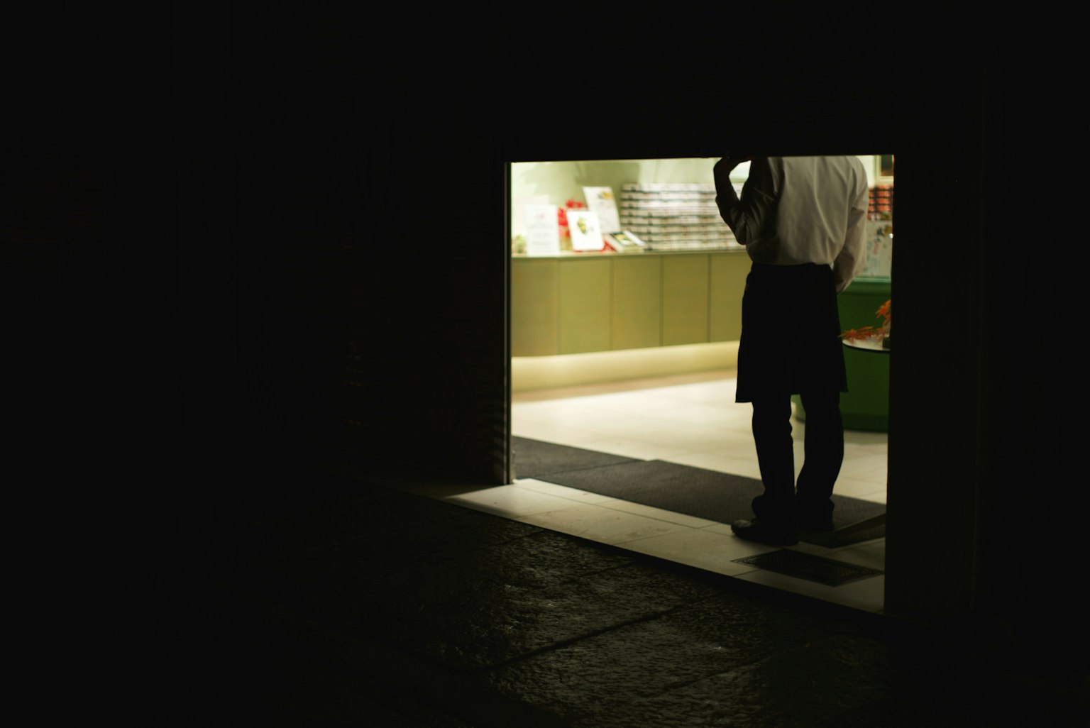 어두운 문에 서 있는 사람의 실루엣과 밝은 상점 내부